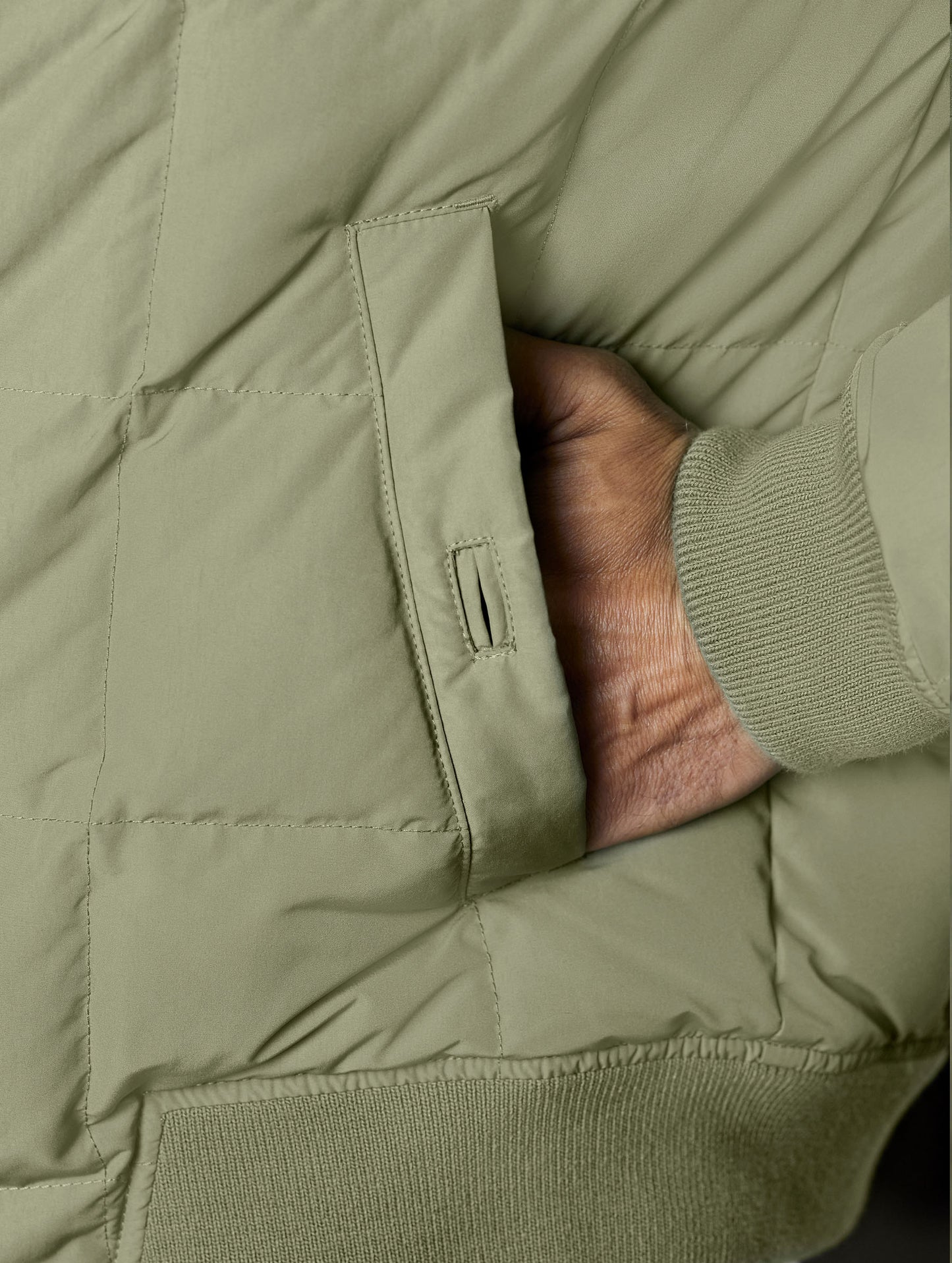 Closeup detailed view of the button-secured hand pocket on the Pacer Jacket in Fern Green from AETHER Apparel.