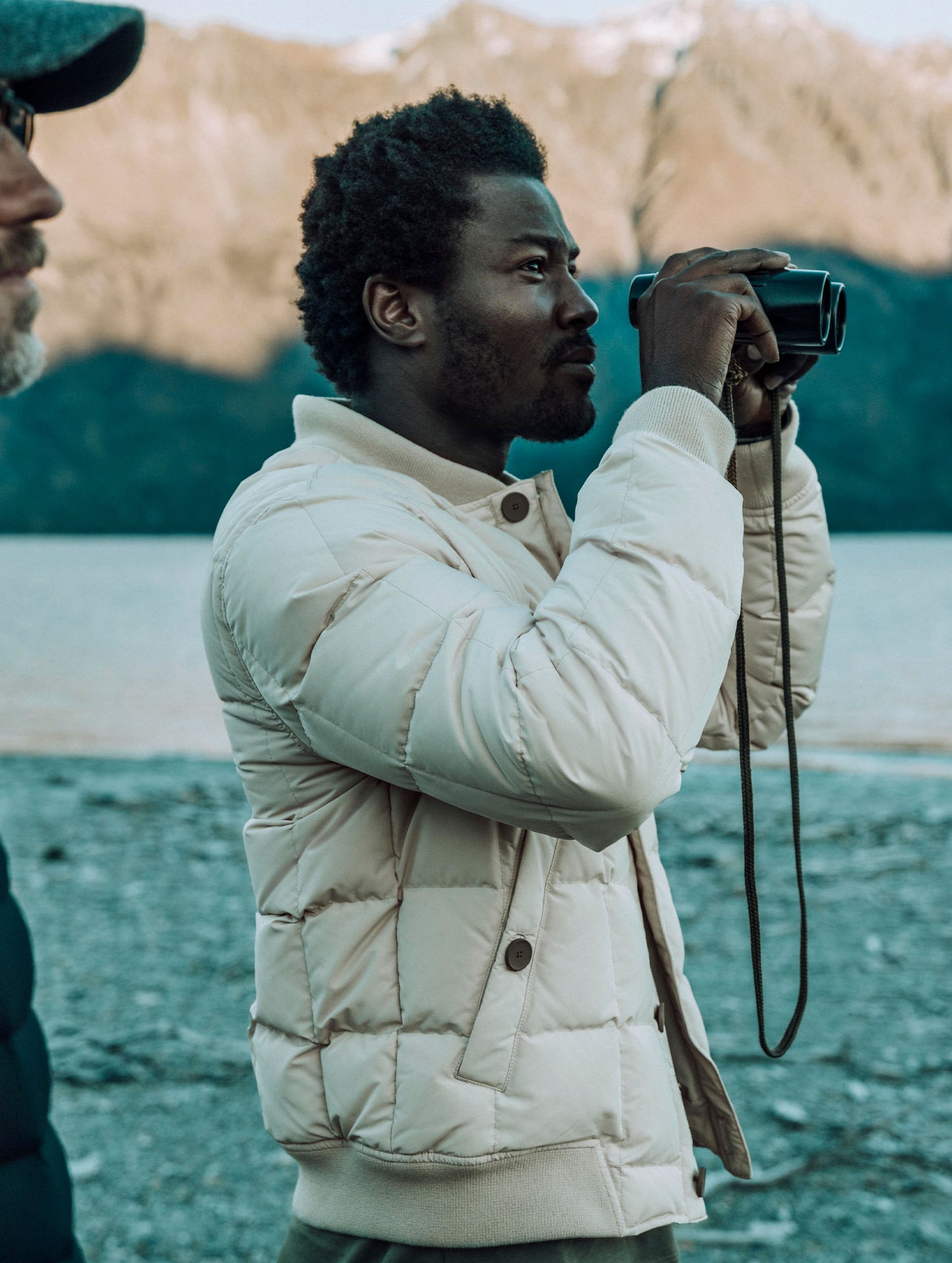 Man holding binoculars wearing the Pacer Jacket in Bone white from AETHER Apparel.