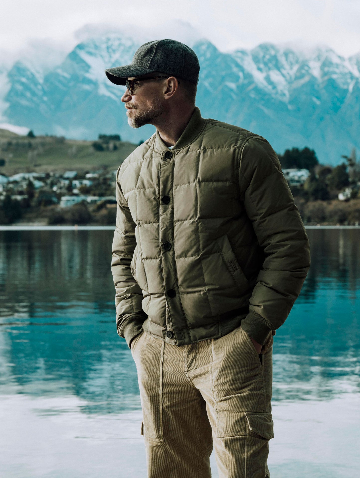 Man standing in front of lake wearing Pacer Jacket in Fern Green from AETHER Apparel.