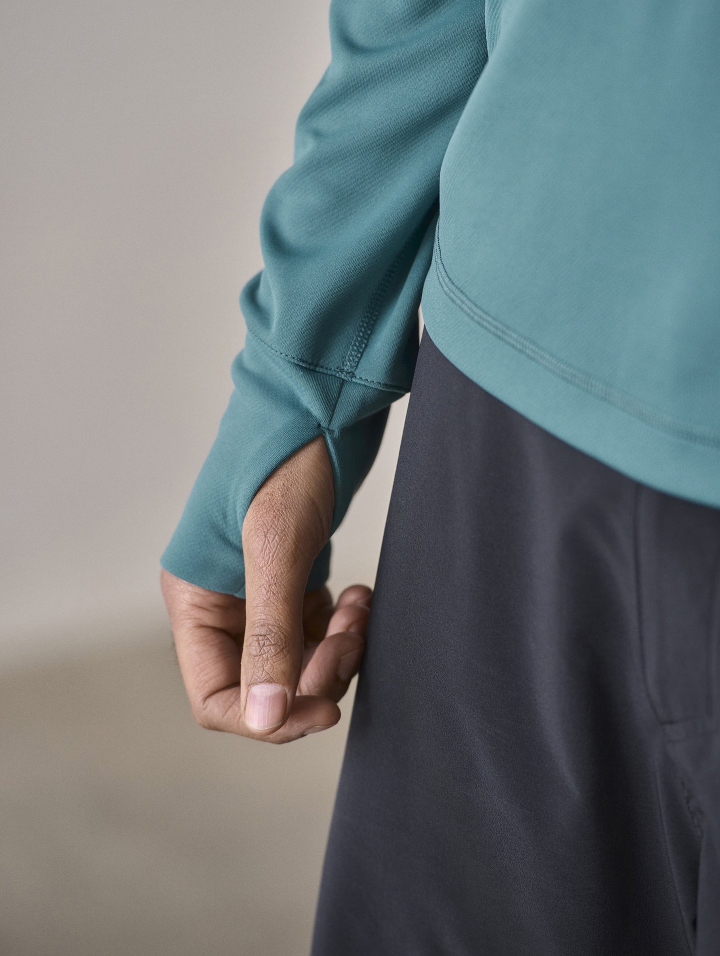 Closeup detailed view of the bartack-reinforced, on-seam thumbhole opening on the Pacific Crewneck Sun Shirt in Aqua Blue from AETHER Apparel.