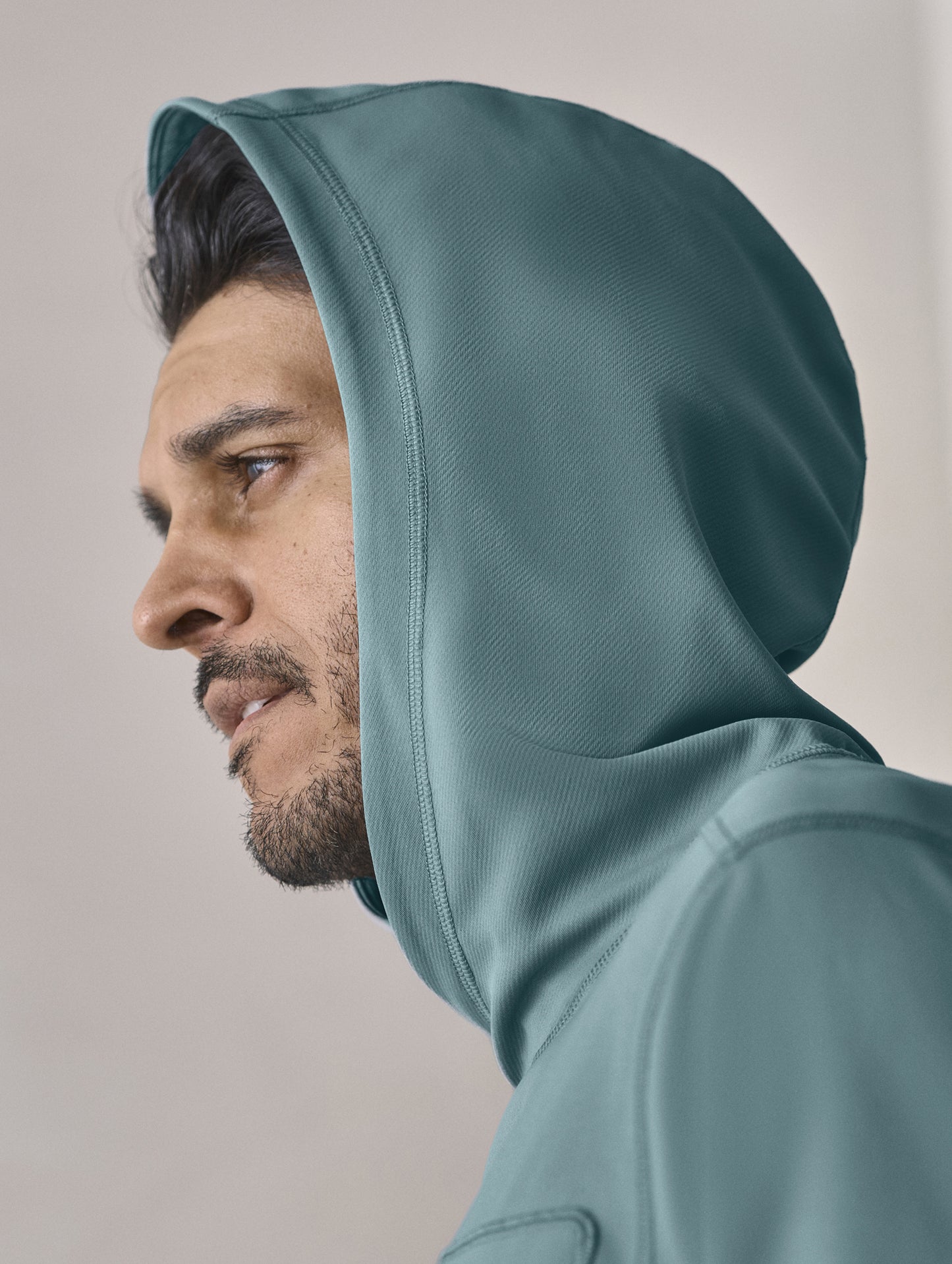 Closeup view of man with hood up wearing the Pacific Hooded Sun Shirt in Aqua Blue from AETHER Apparel.