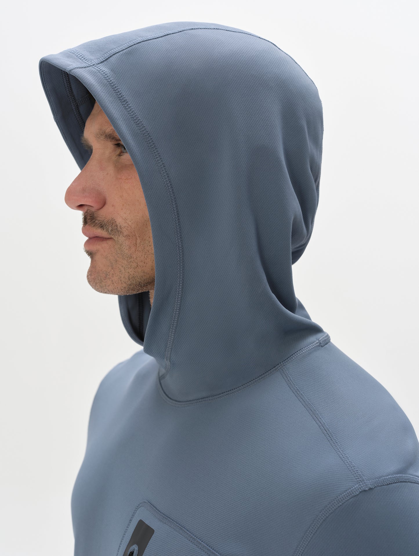 Closeup view of man with hood up wearing the Pacific Hooded Sun Shirt in Portal Blue from AETHER Apparel.