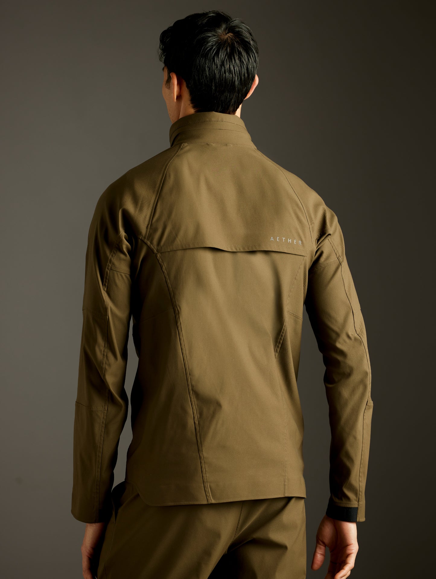 Rear 3/4 body view of man wearing Perth Vented Jacket in Cadet Green from AETHER Apparel.
