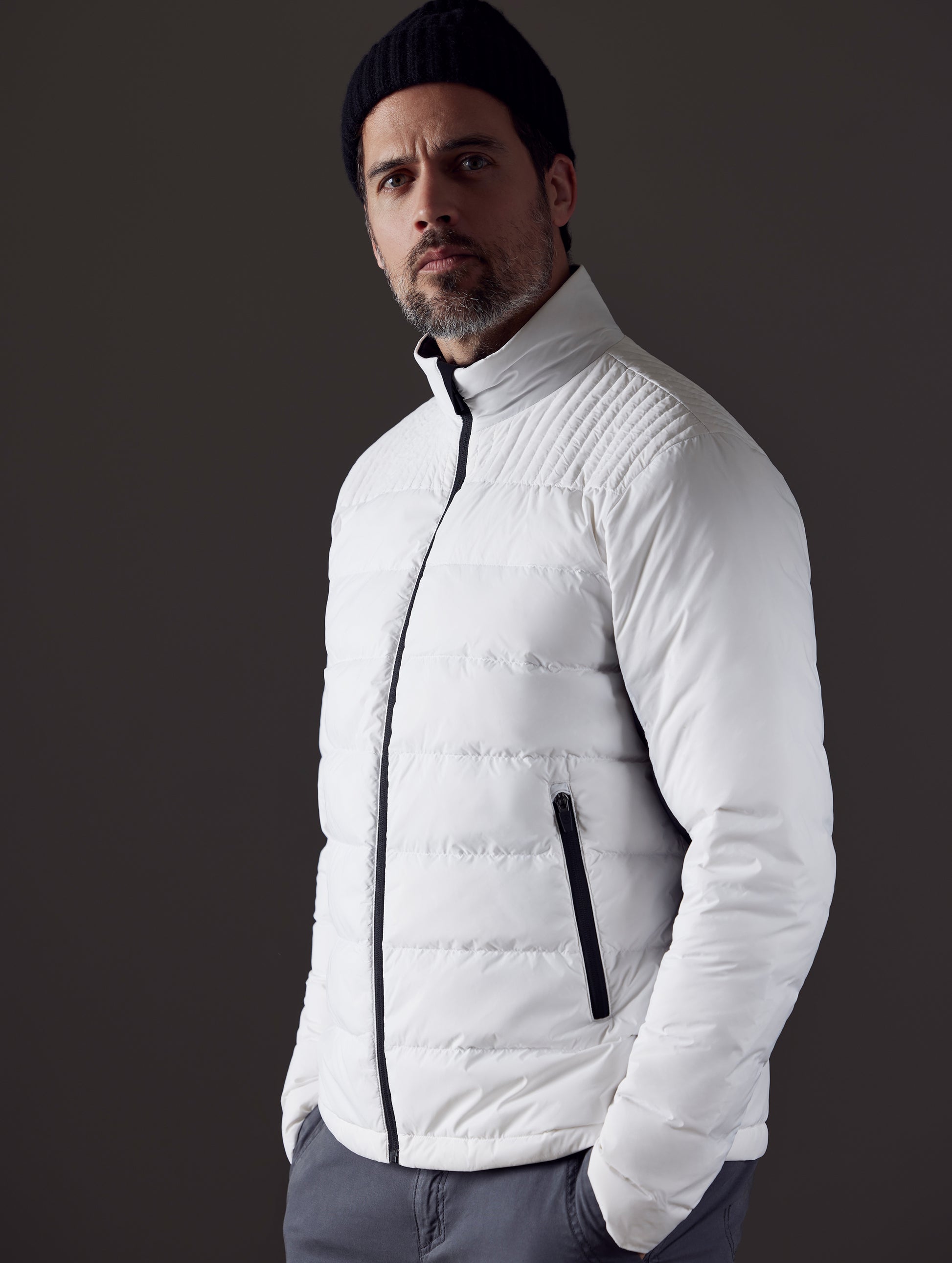 Front 3/4 body view of man with hands in pant pockets wearing Phantom Jacket in White from AETHER Apparel.