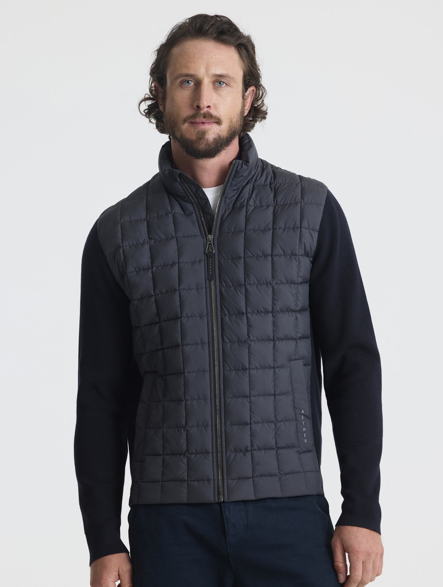 Front, upper-body view of man wearing zipped-up M Phase Full-Zip in Onyx Black from AETHER Apparel.