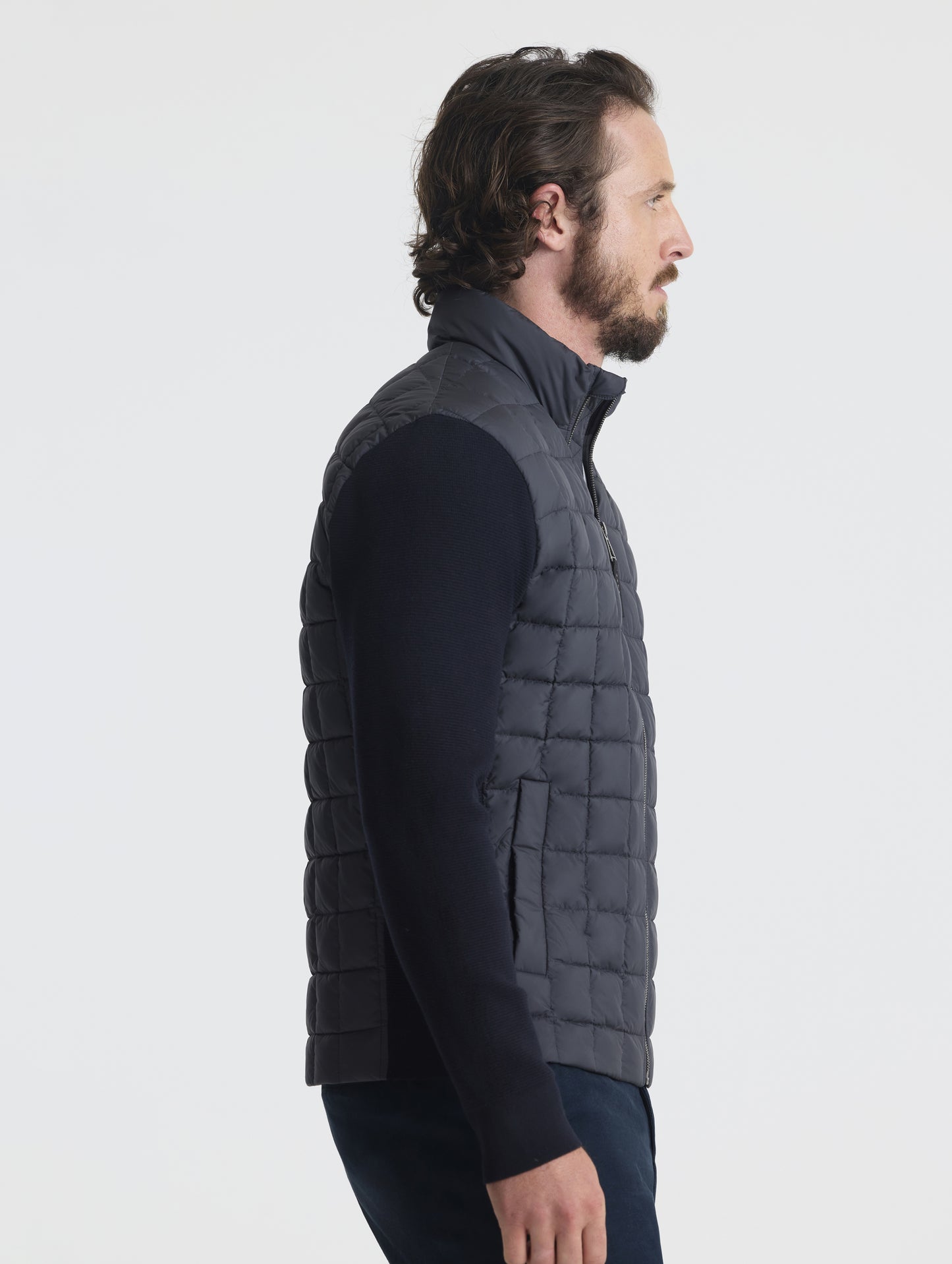 Side, profile upper-body view of man wearing M Phase Full-Zip in Onyx Black from AETHER Apparel.