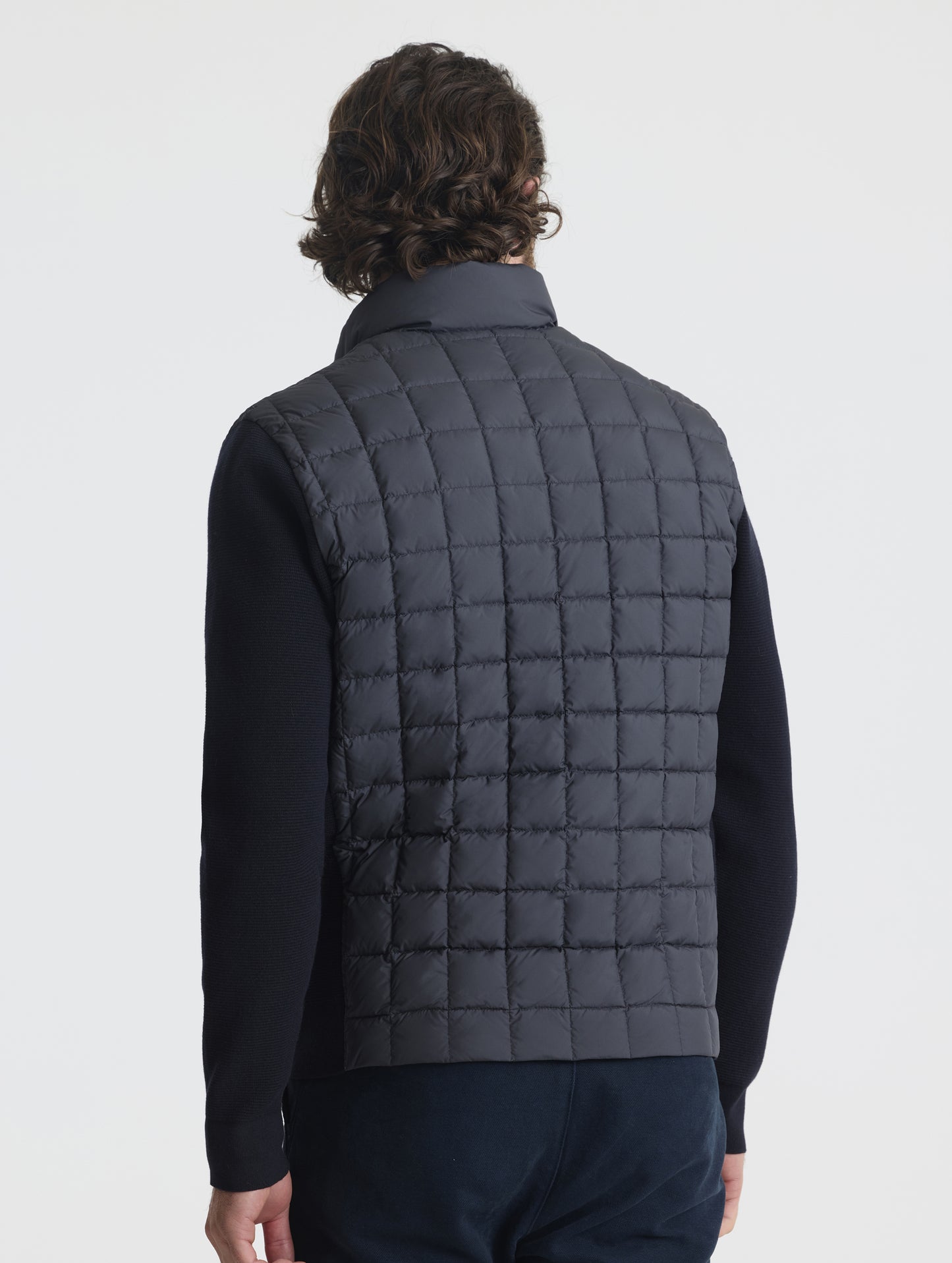 Rear, angled, upper-body view of man wearing M Phase Full-Zip in Onyx Black from AETHER Apparel.