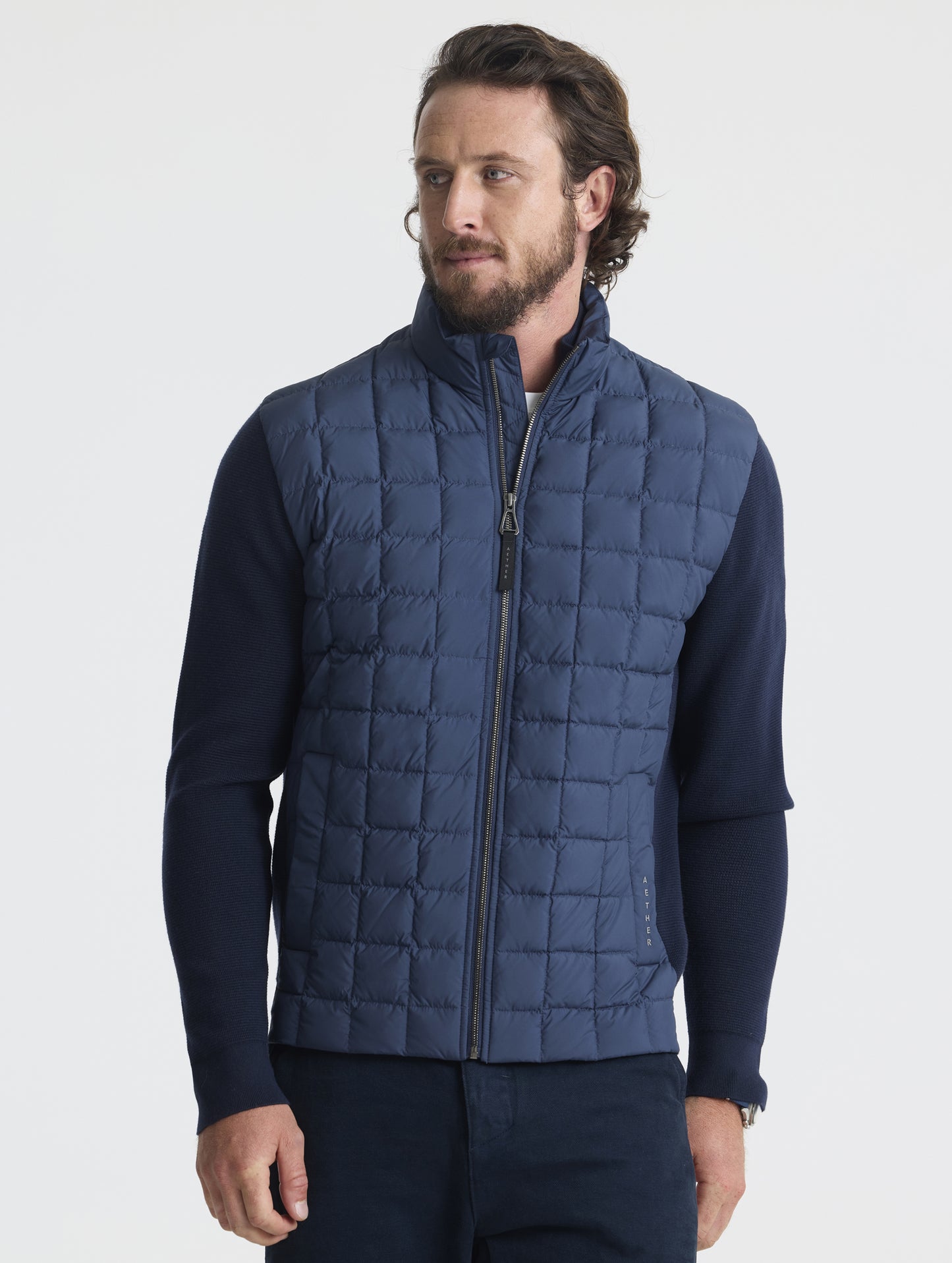 Front upper-body view of man wearing zipped-up M Phase Full-Zip in Total Eclipse dark blue from AETHER Apparel.
