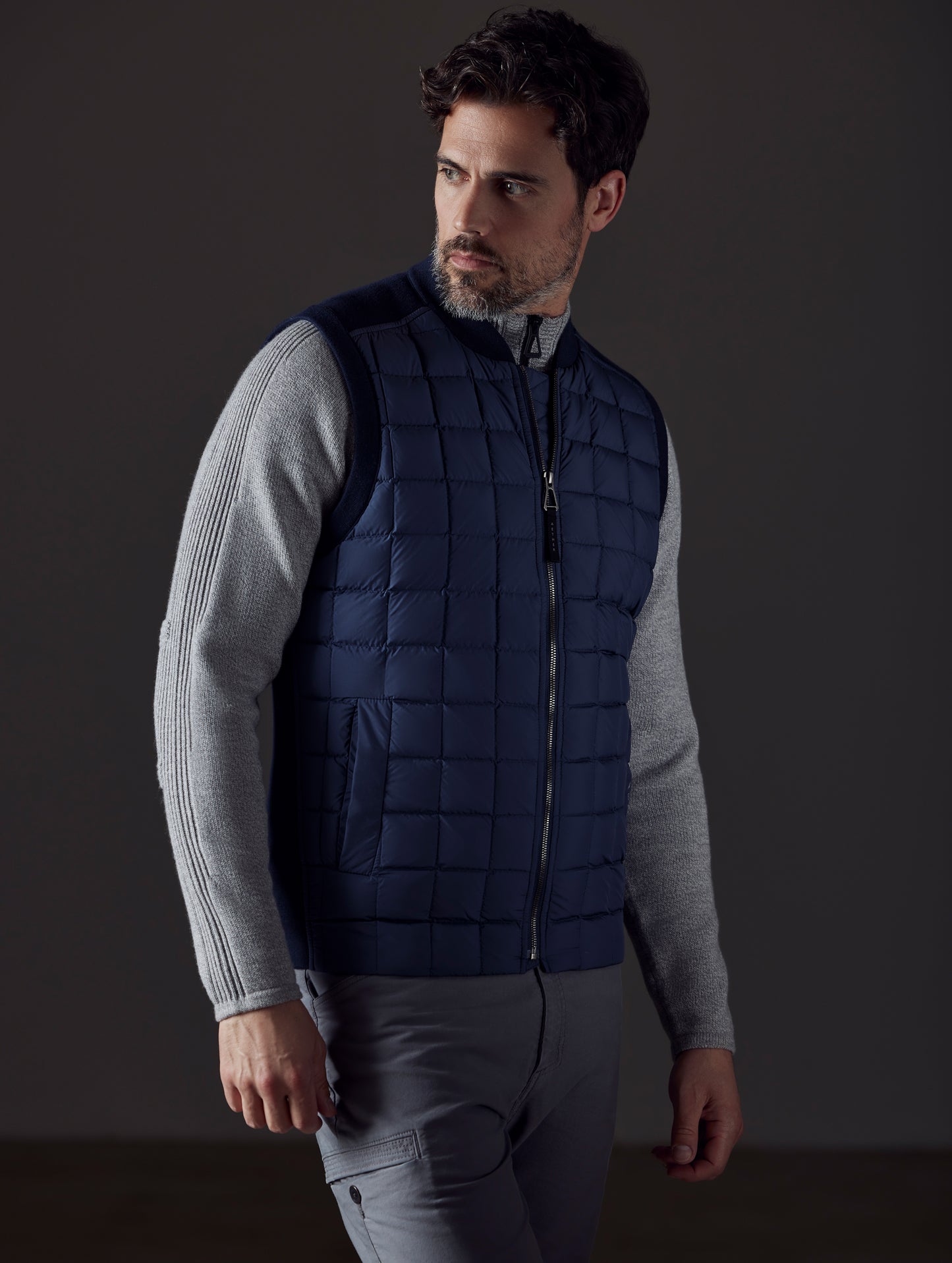 Front 3/4 body view of man looking over shoulder wearing Phase Vest in Total Eclipse dark blue from AETHER Apparel.