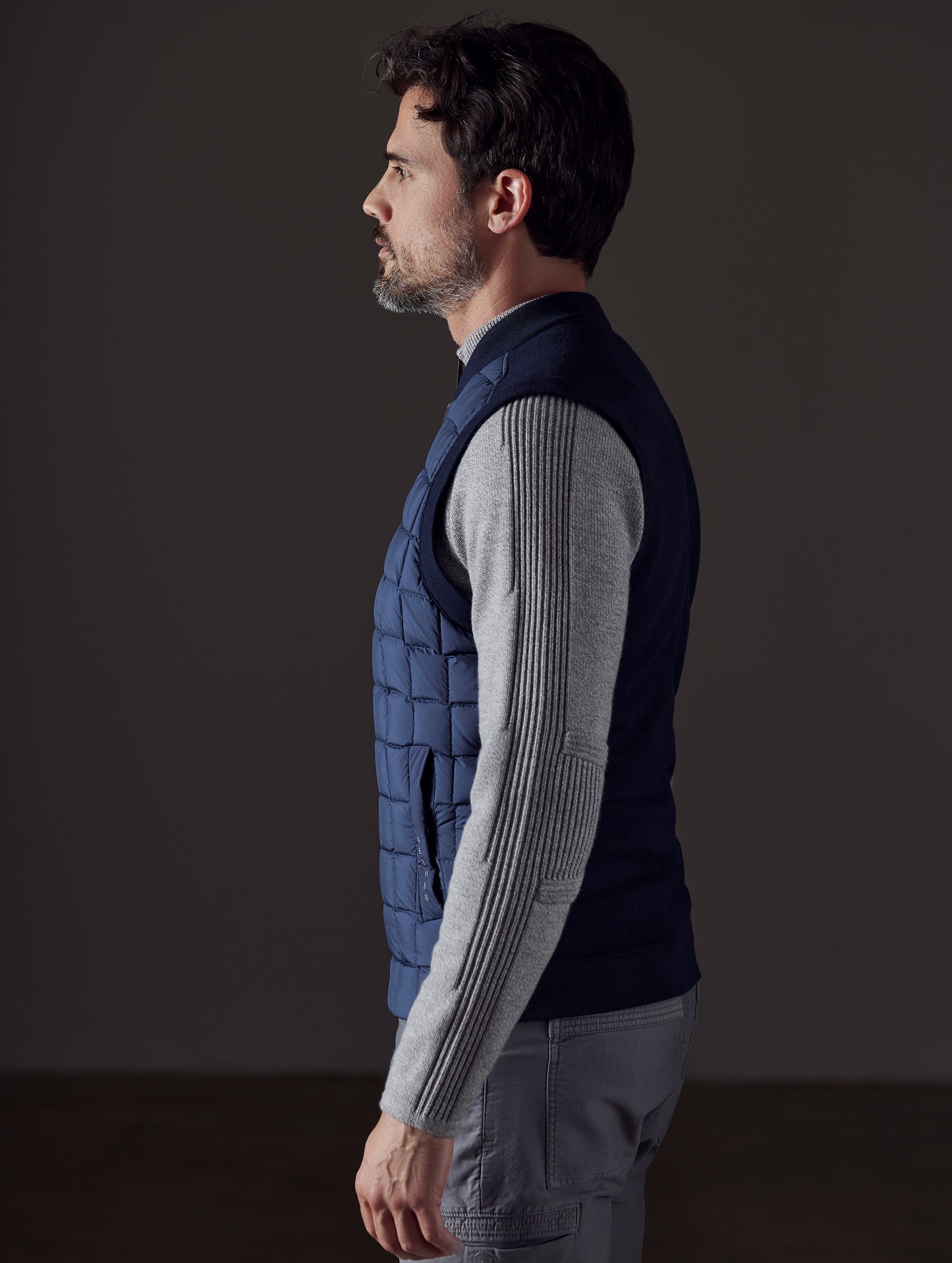Side profile body view of man wearing Phase Vest in Total Eclipse dark blue from AETHER Apparel.