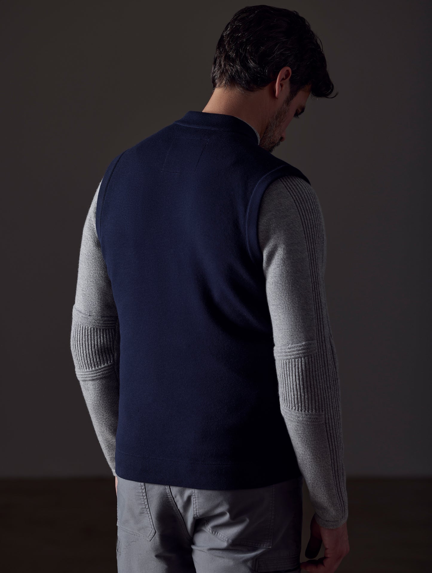 Rear 3/4 body view of man wearing Phase Vest in Total Eclipse dark blue from AETHER Apparel.