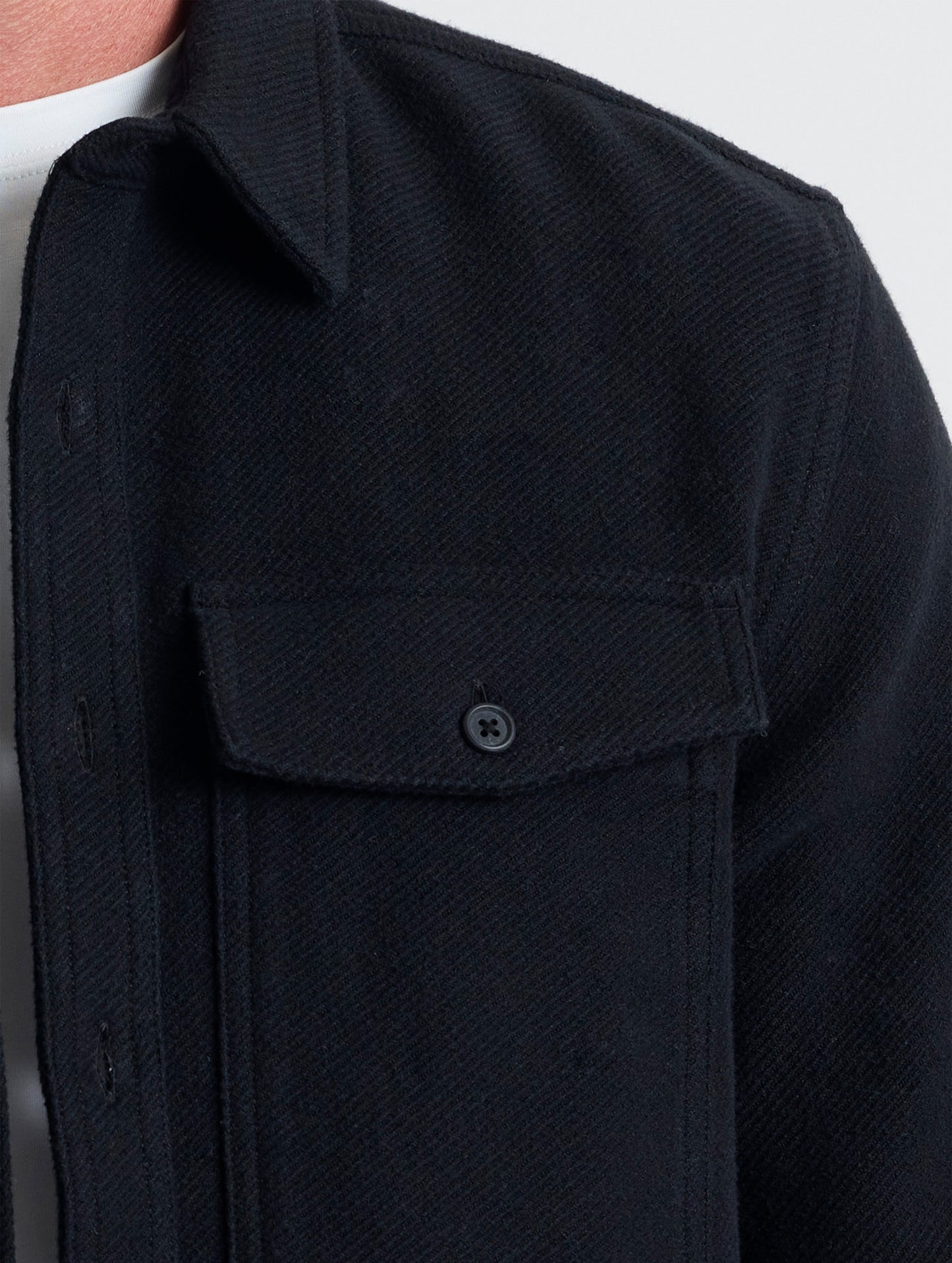 Closeup detailed view of the button-secured chest patch pockets on the Pioneer Heavyweight Button-Down in Onyx Black from AETHER Apparel.