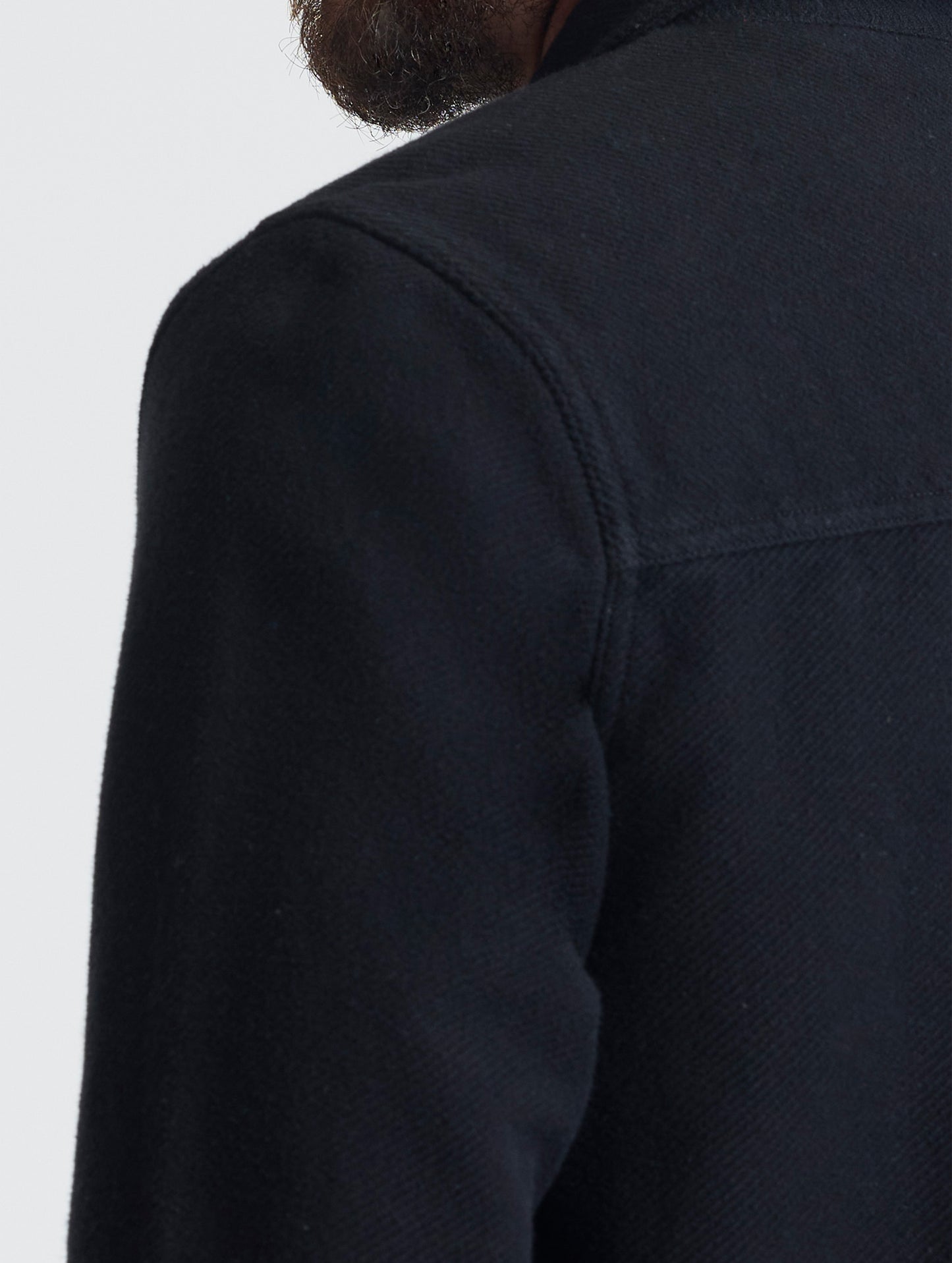 Closeup detailed view of the forward shoulder seams on the Pioneer Heavyweight Button-Down in Onyx Black from AETHER Apparel.