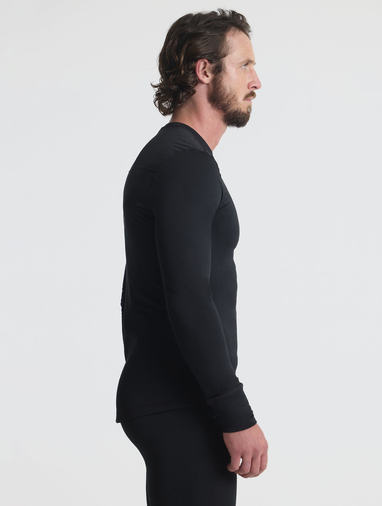 Side profile upper-body view of man wearing Polar Base Layer Crew in Onyx Black from AETHER Apparel.
