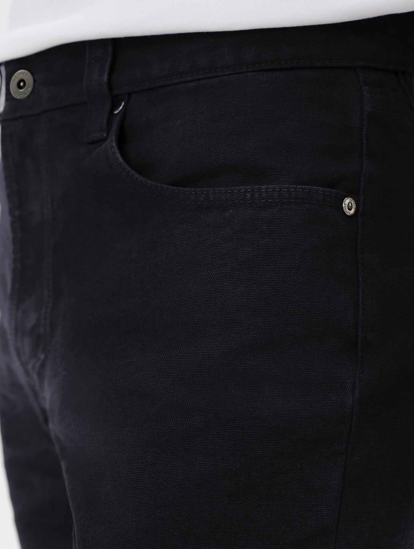 Closeup detailed view of the custom AETHER-branded rivets and shank button closure on the Porter 5-Pocket Pant in Onyx Black from AETHER Apparel.