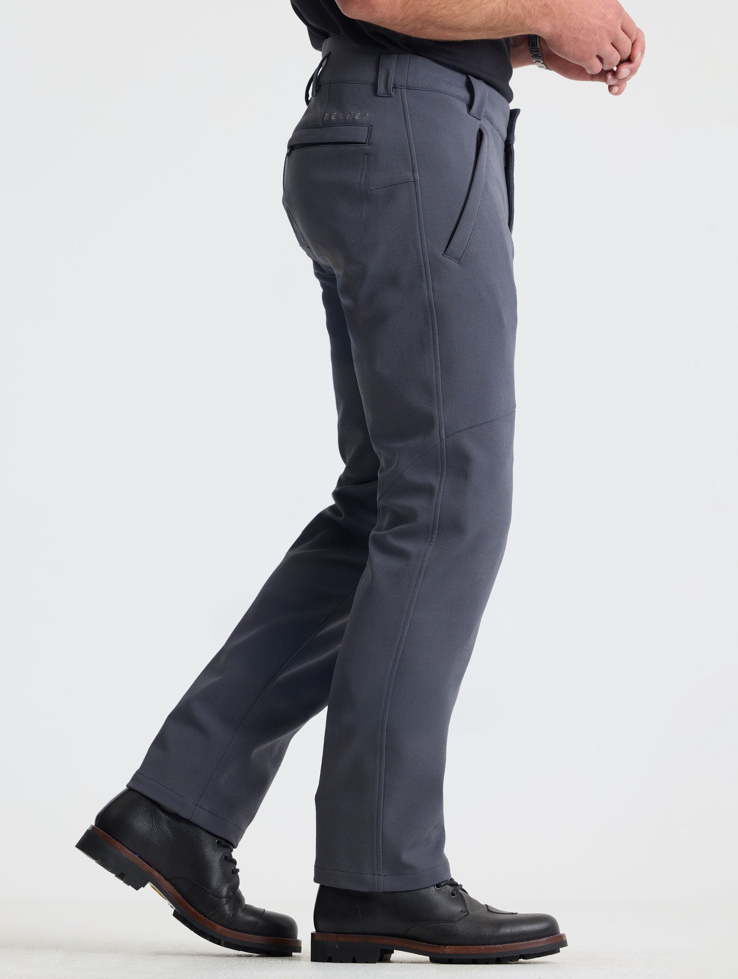 Side profile lower-body view of man wearing Ramble Pant 3.0 in Graphite from AETHER Apparel.