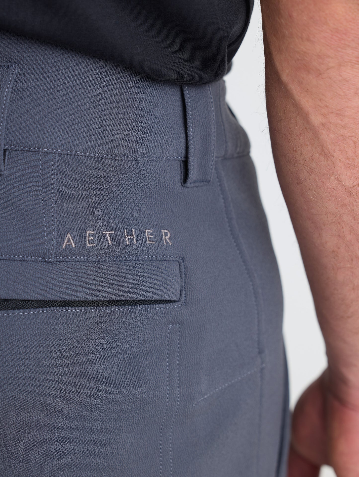 Closeup detailed view of one of the zipper-secured single welt back pockets on the Ramble Pant 3.0 in Graphite from AETHER Apparel.