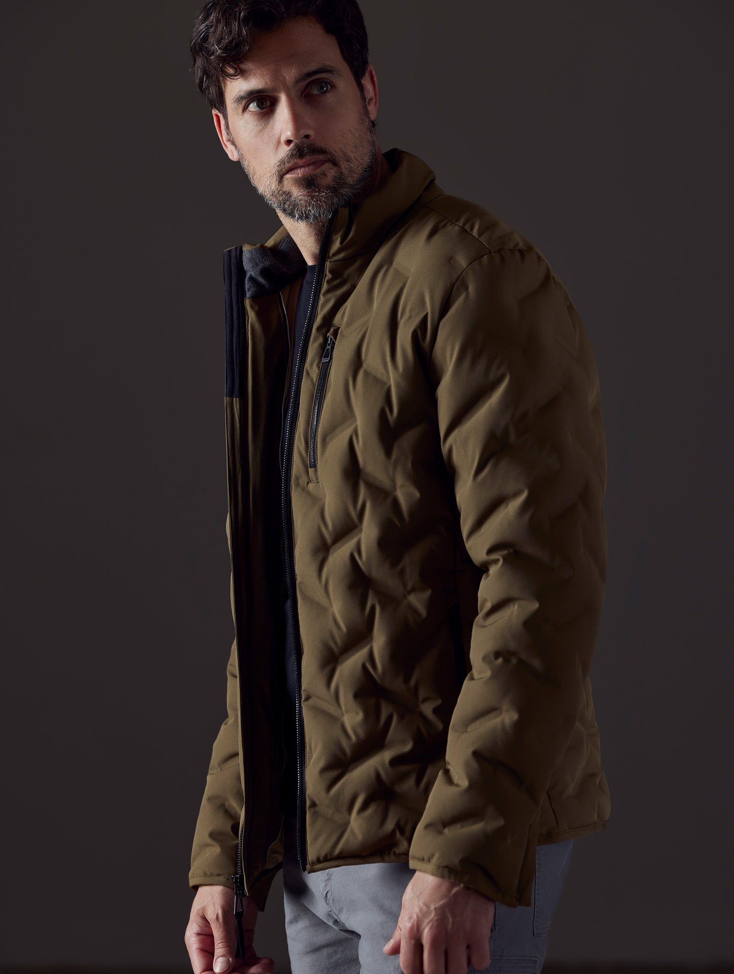 Side profile body view of man wearing Rex Down Jacket in Command Greenfrom AETHER Apparel.