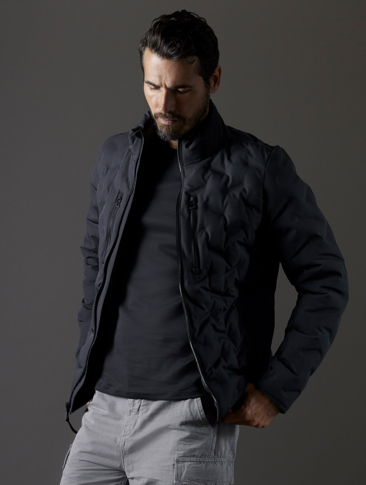 Front 3/4 body view of man wearing unzipped Rex Down Jacket in Onyx Black  from AETHER Apparel.