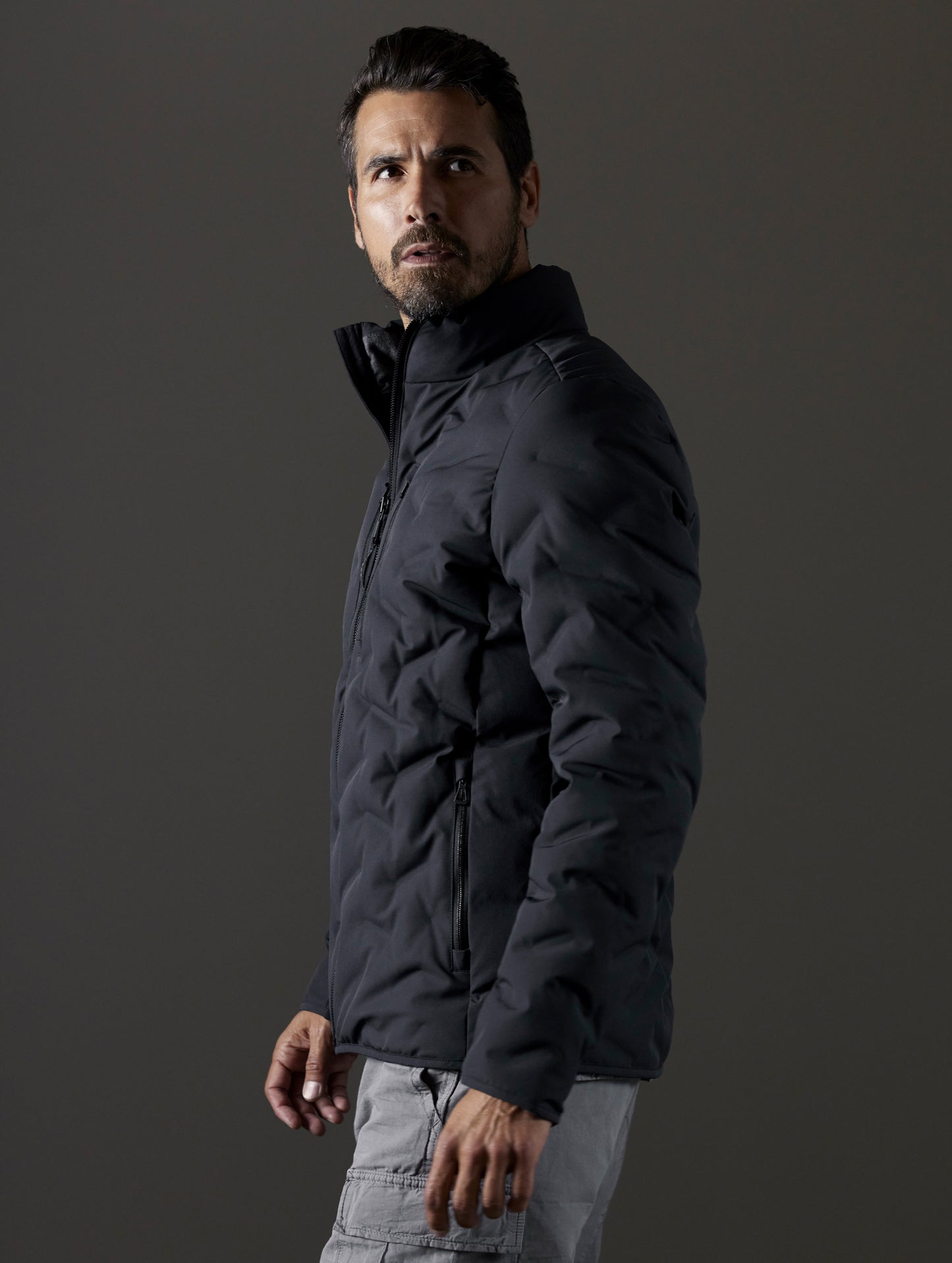 Side profile body view of man wearing Rex Down Jacket in Onyx Black from AETHER Apparel.