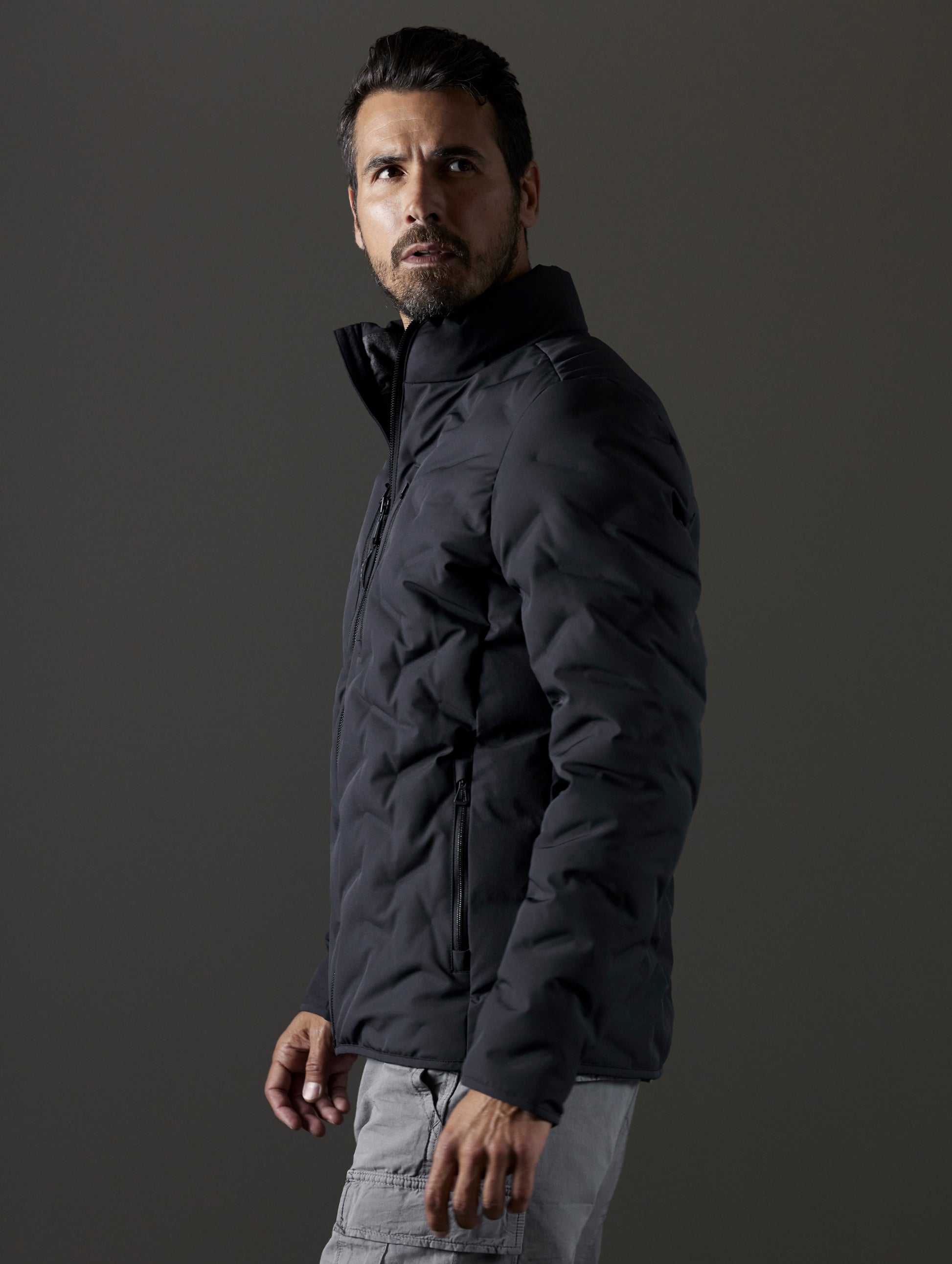 Side profile body view of man wearing Rex Down Jacket in Onyx Black  from AETHER Apparel.