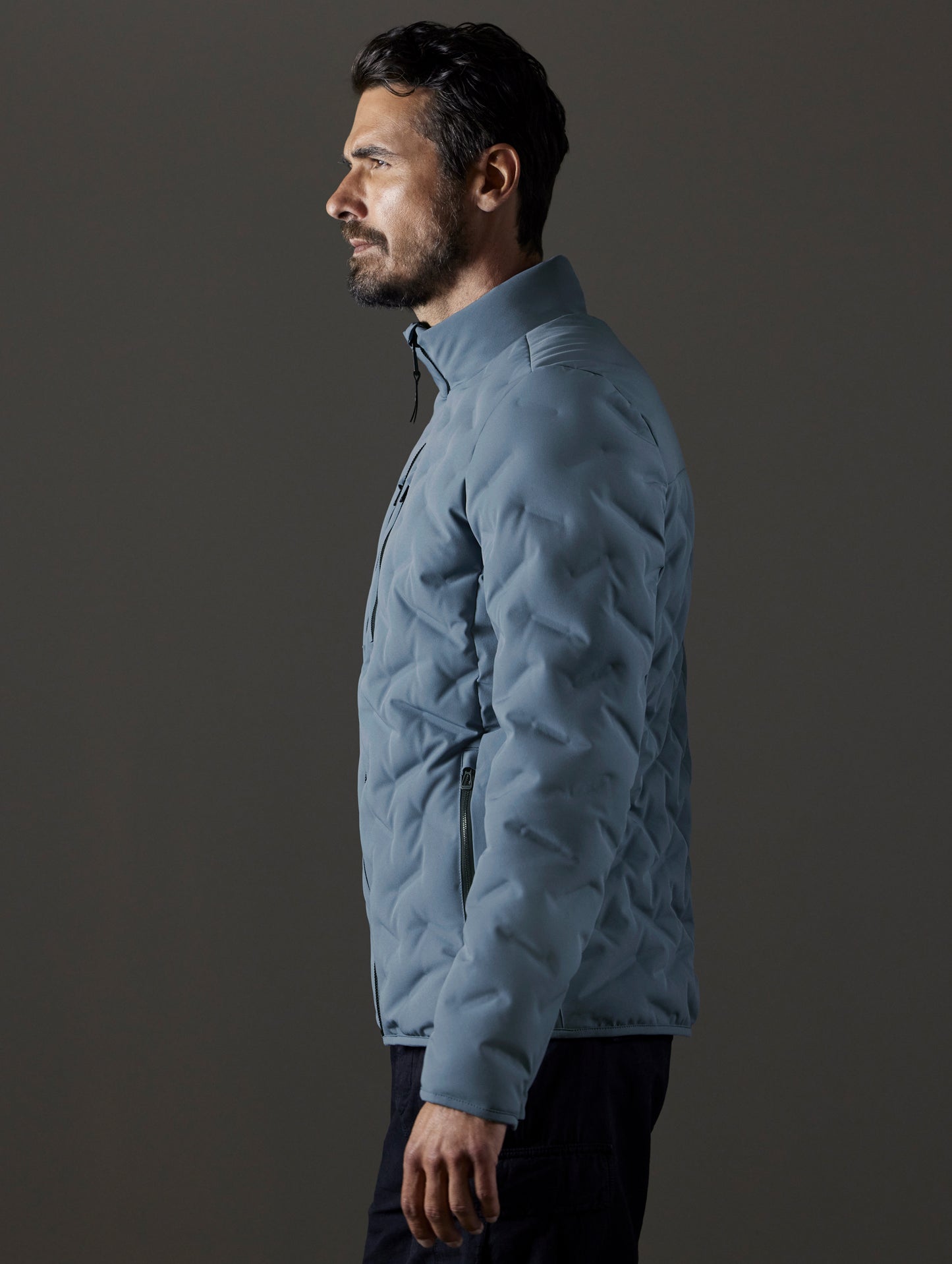 Side profile body view of man wearing Rex Down Jacket in Portal Blue from AETHER Apparel.