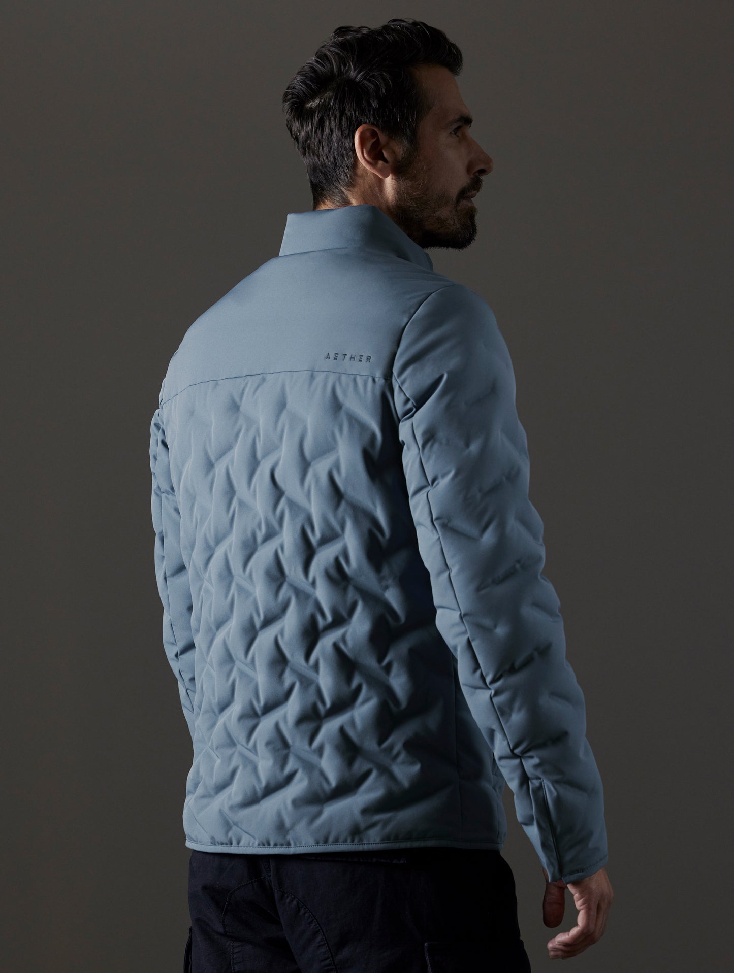 Rear 3/4 body view of man wearing Rex Down Jacket in Portal Blue from AETHER Apparel.