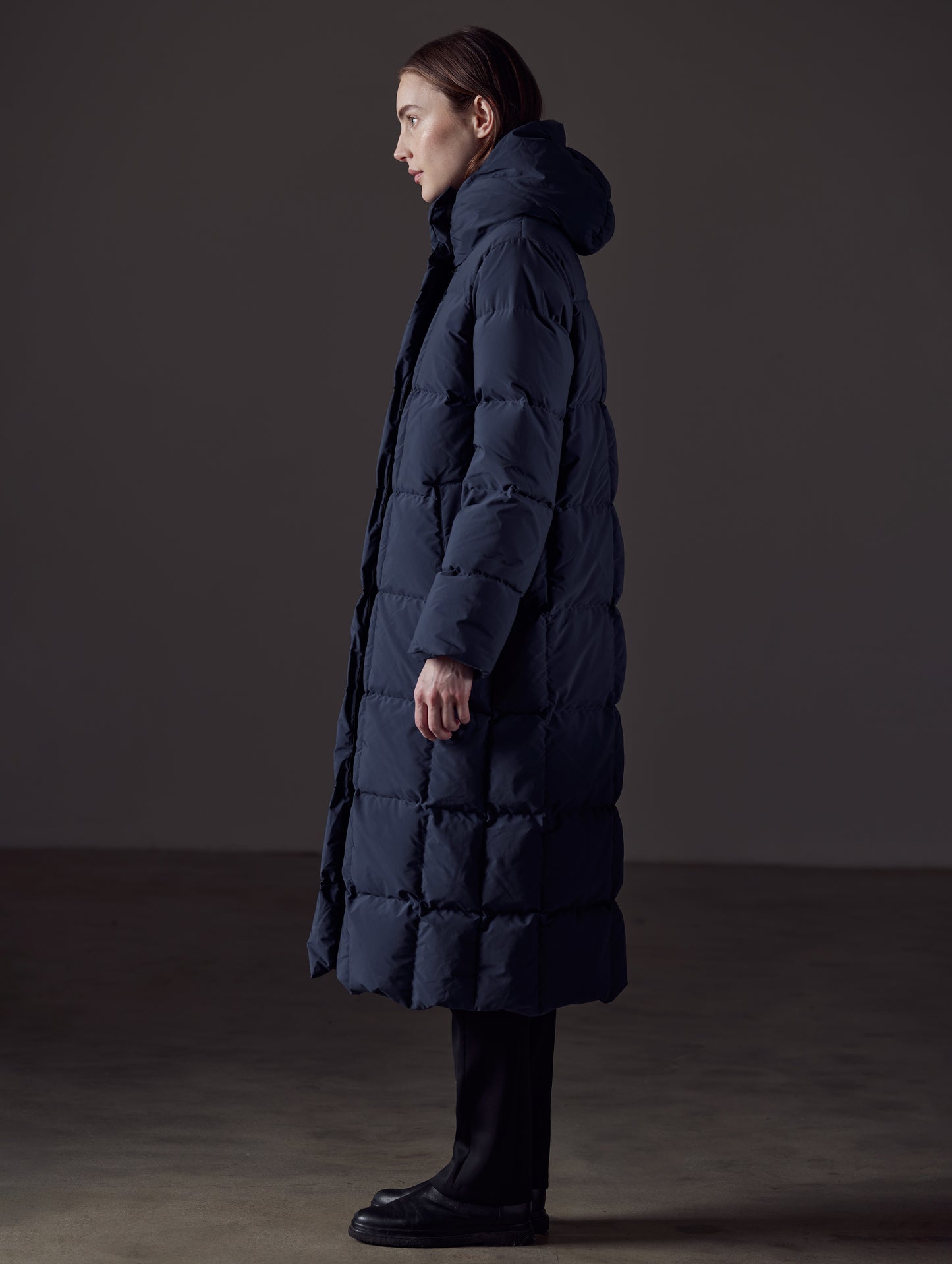 Side profile full-body view of woman wearing Shaw Jacket in Nordic Navy Blue from AETHER Apparel.