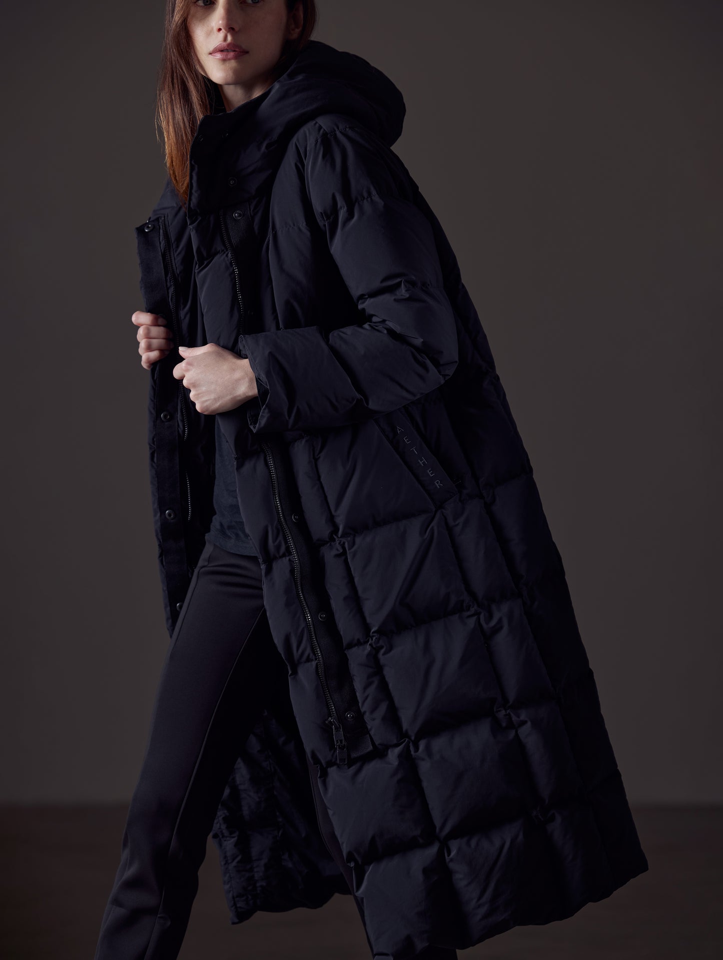Side profile image of woman walking wearing open Shaw Jacket in Onyx Black from AETHER Apparel.