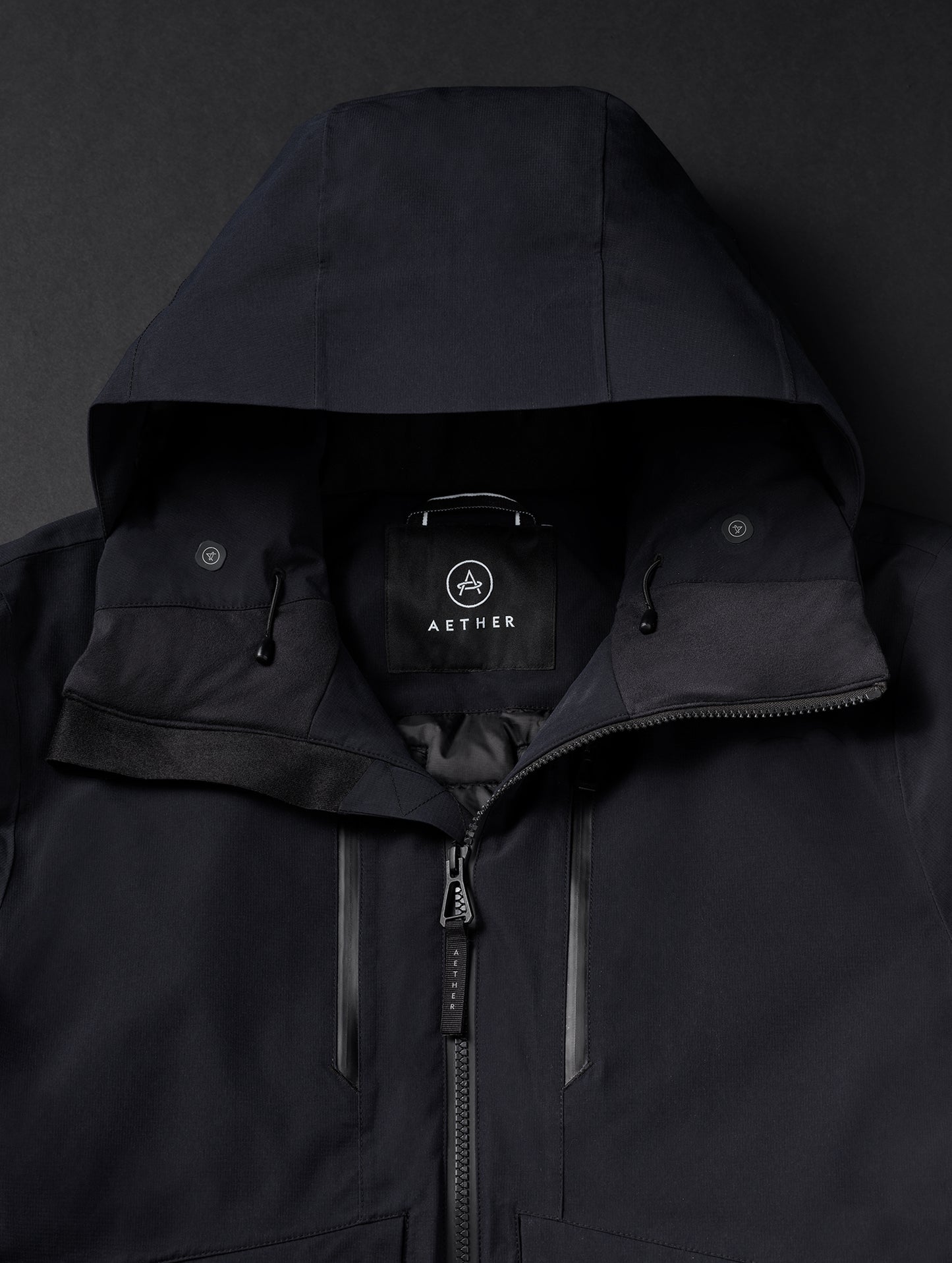 Closeup flat lay of shoulders and hood of men's Silverton Down Jacket in Onyx Black from AETHER Apparel.