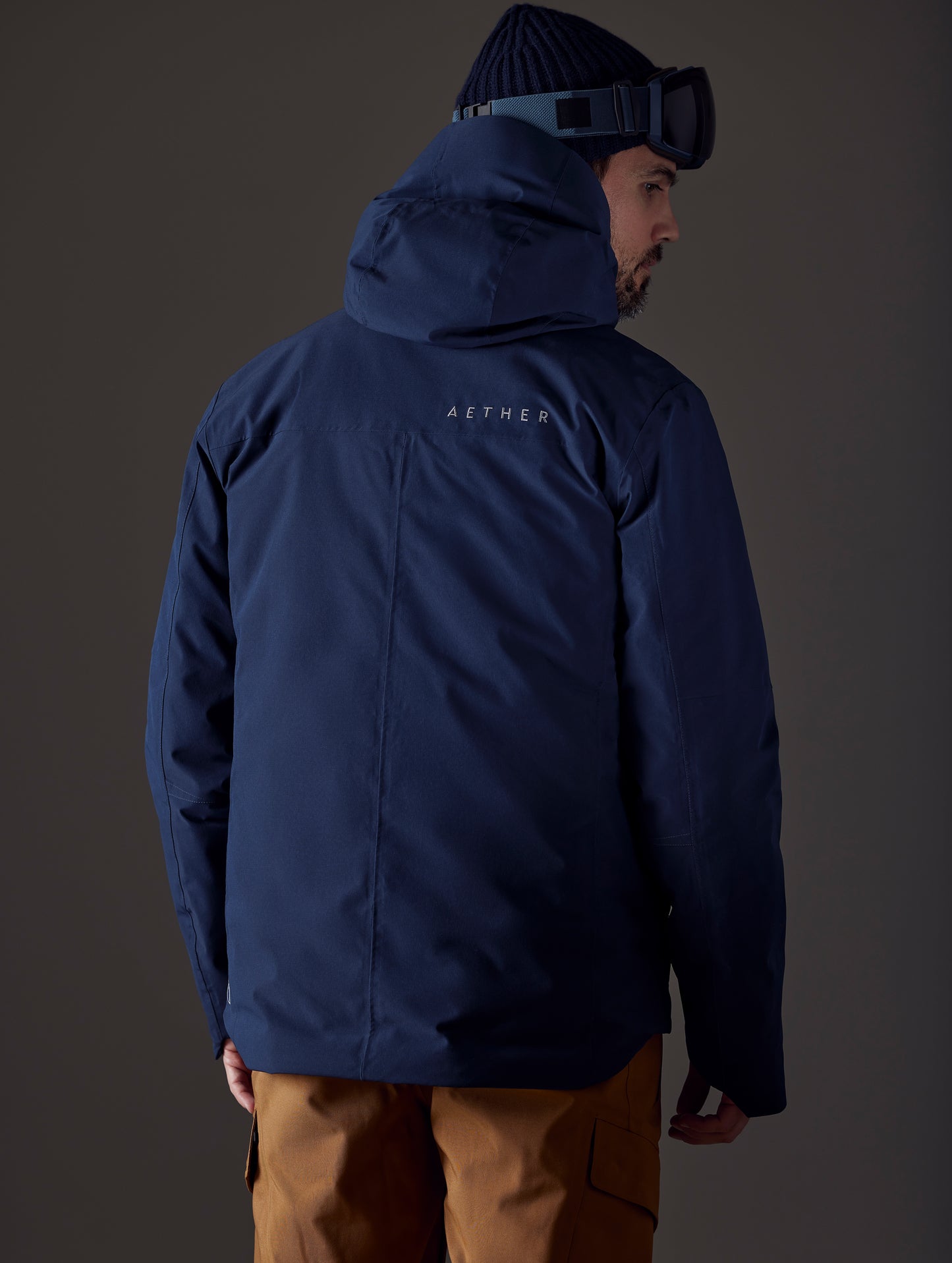 Rear body view of man wearing Silverton Down Jacket in Total Eclipse dark blue from AETHER Apparel.