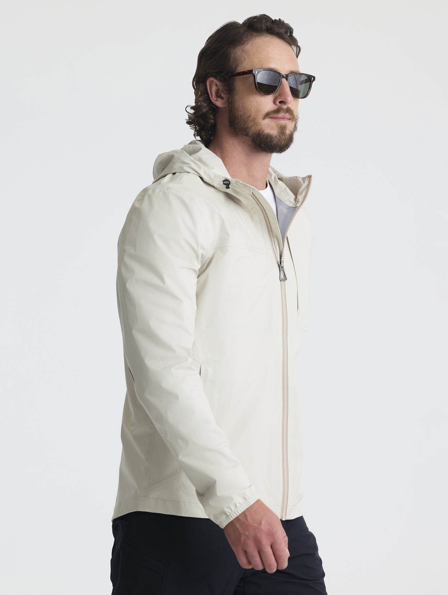 3/4 view of man wearing Storm All-Weather Jacket in Bone white from AETHER Apparel.