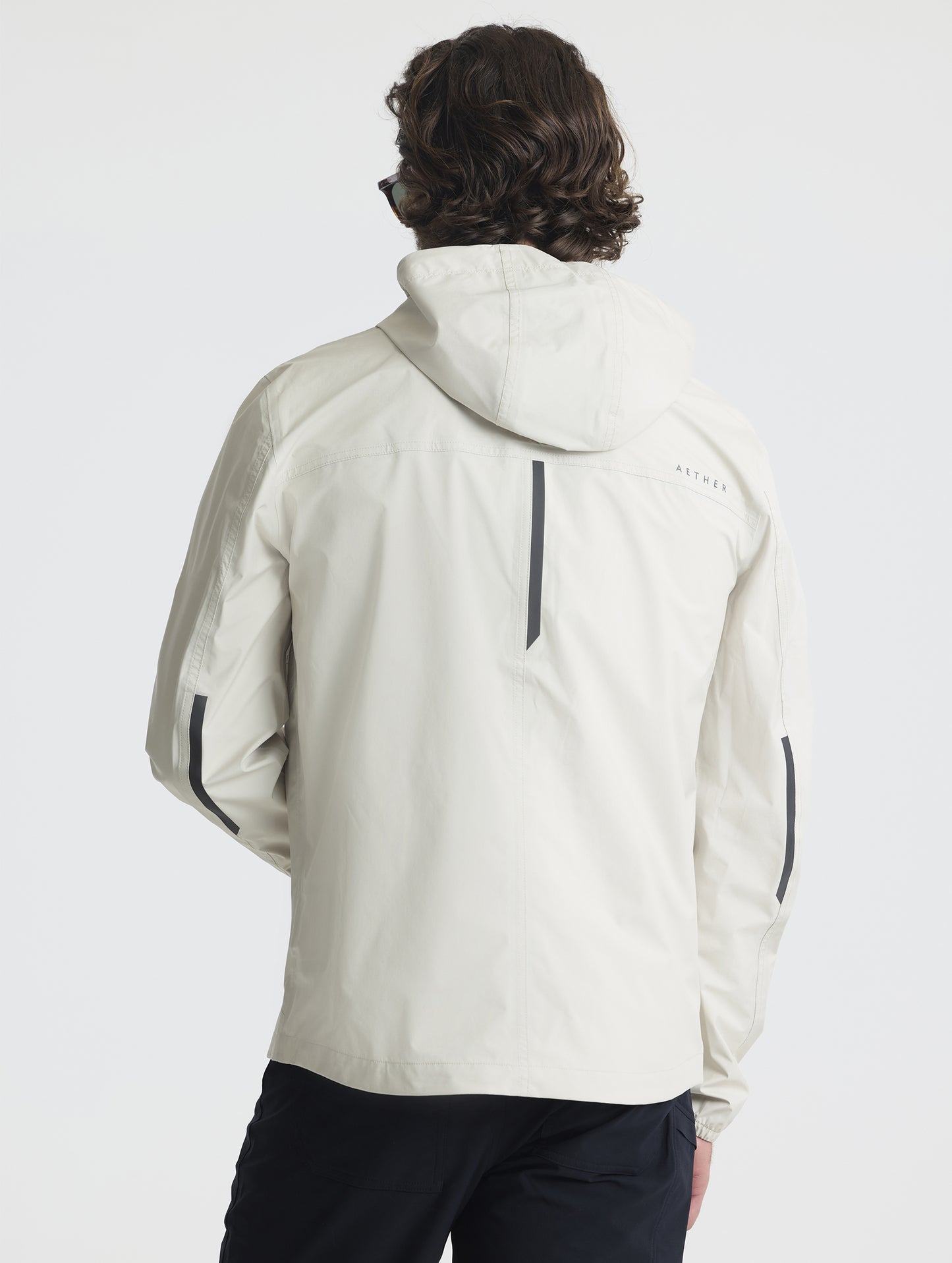 Rear view of man wearing Storm All-Weather Jacket in Bone white from AETHER Apparel.