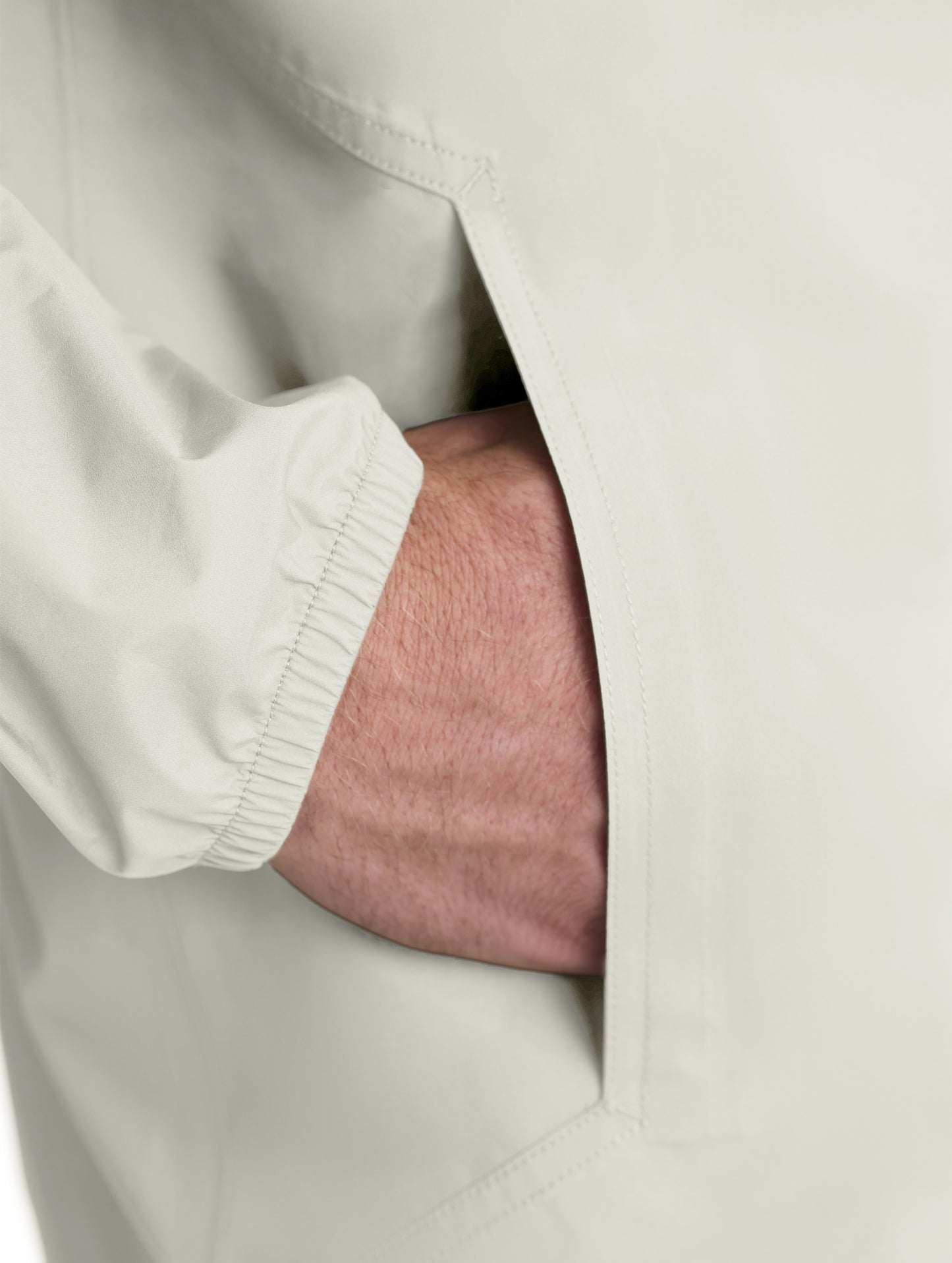 Closeup of wearer's right hand in pocket of Storm All-Weather Jacket in Bone white from AETHER Apparel.
