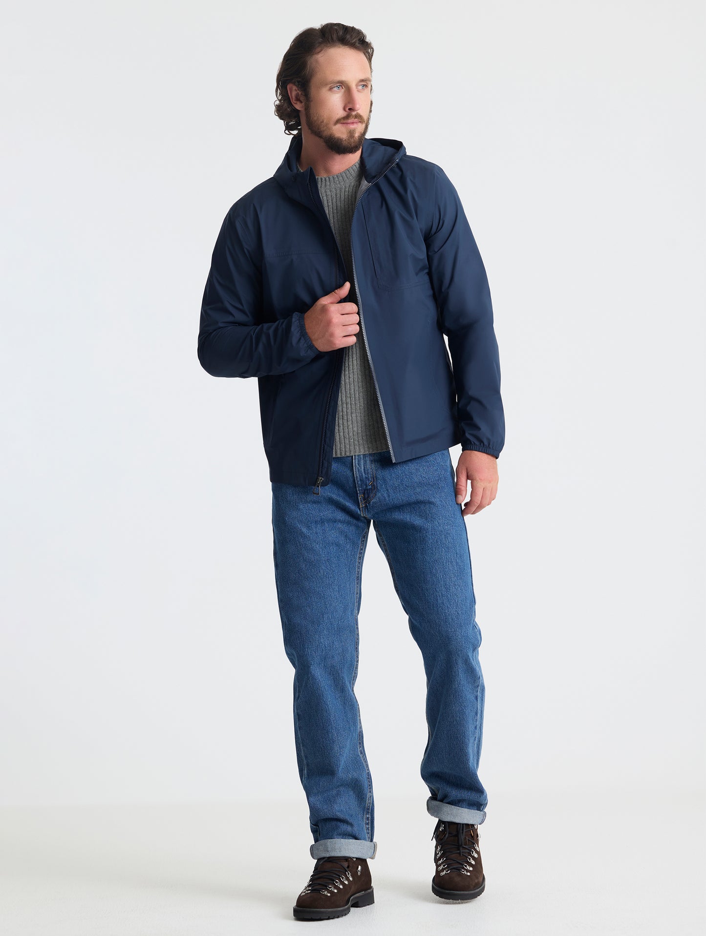 Full body view of man wearing Storm All-Weather Jacket in Total Eclipse dark blue from AETHER Apparel.