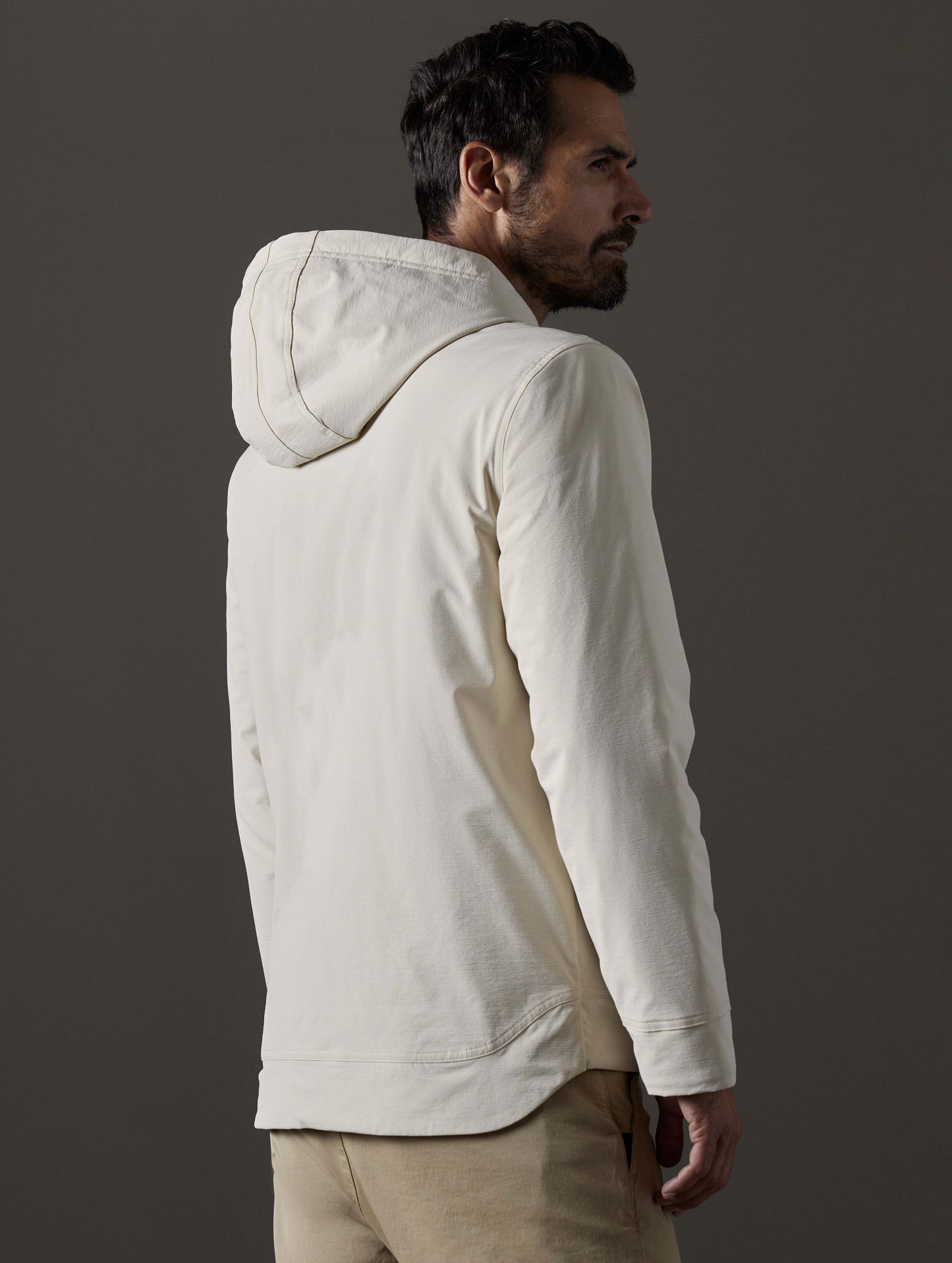 Rear 3/4 body view of man wearing Stornaway Insulated Hoodie in Bone white from AETHER Apparel.
