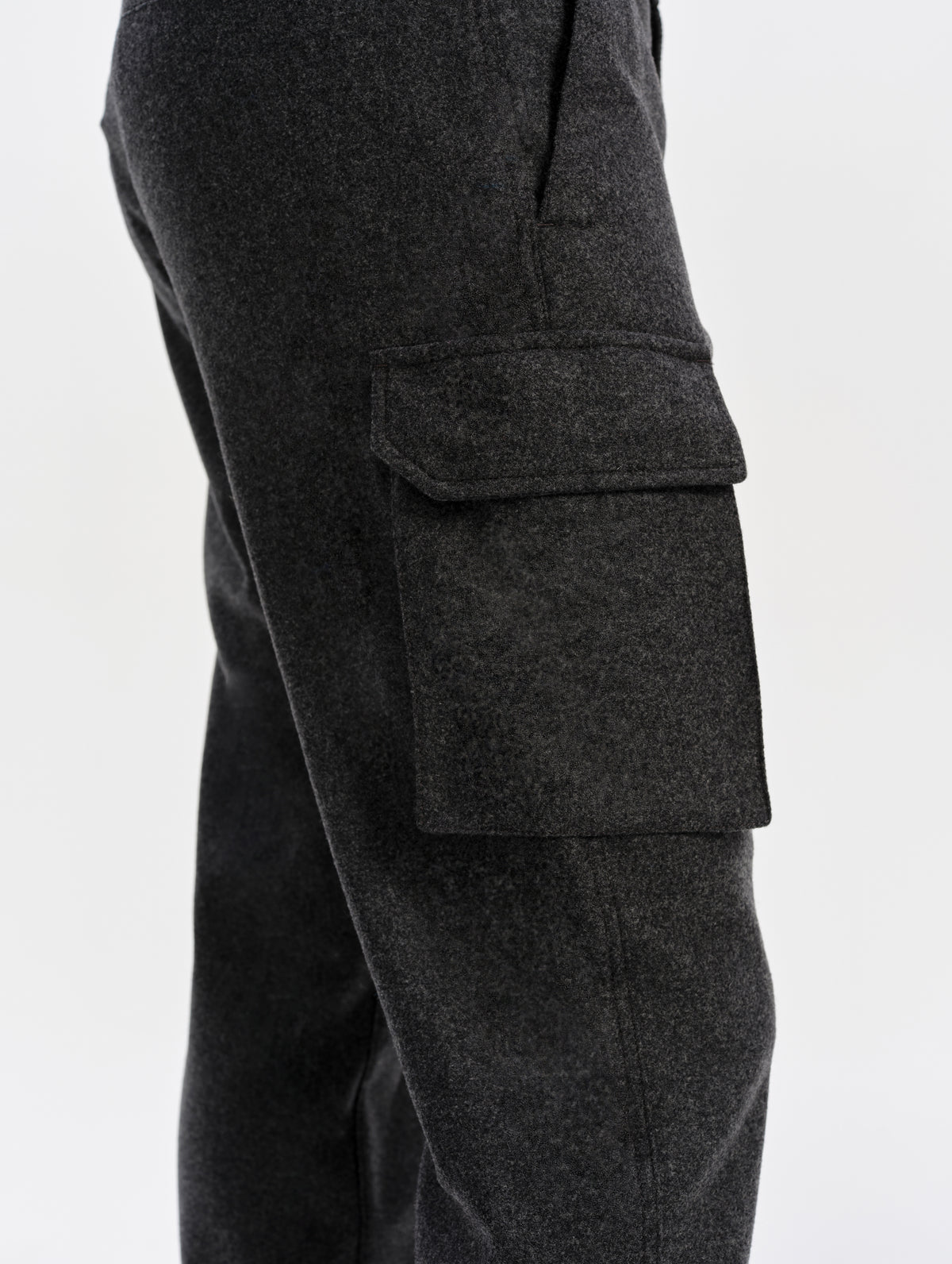 Closeup detailed view of the cargo pockets with hidden button-secured closures on the Strata Wool Pant in Charcoal Heather from AETHER Apparel.
