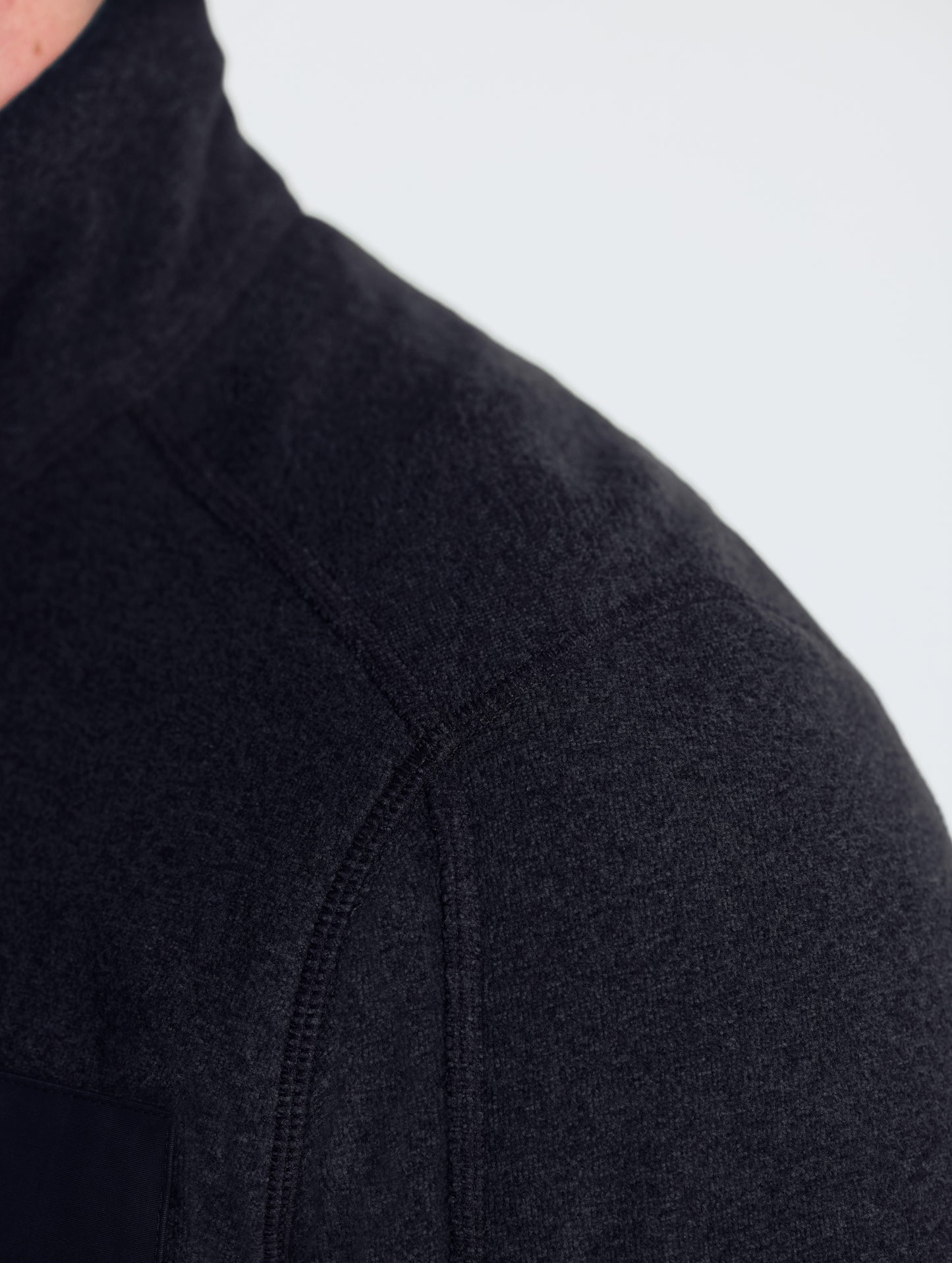 Closeup view of wearer's left shoulder of Sutherlin Full-Zip in Onyx Black from AETHER Apparel.