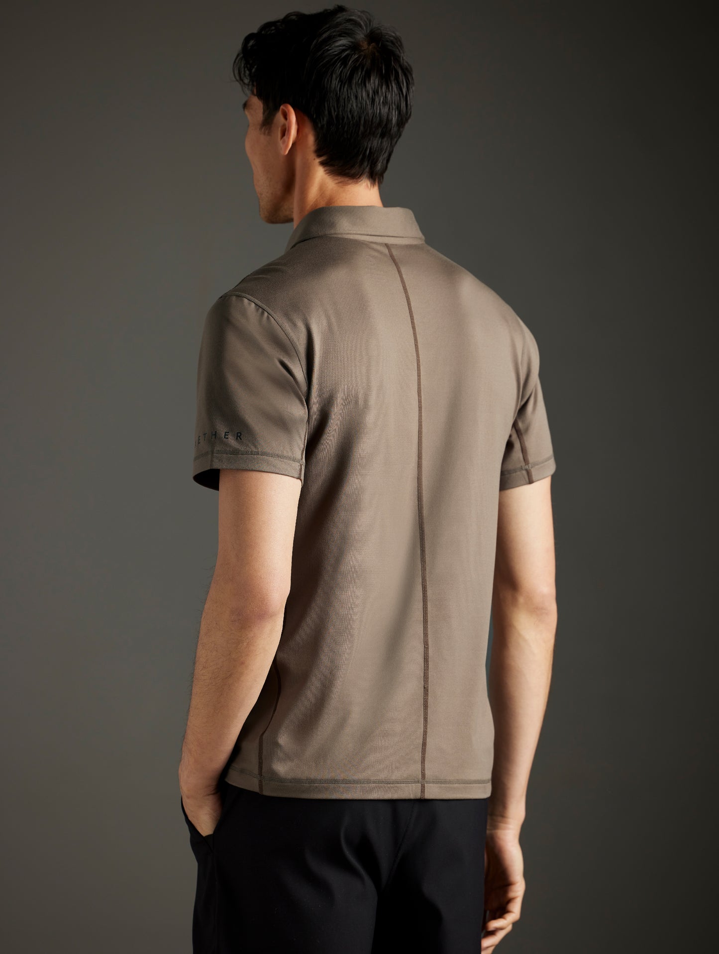 Rear 3/4 body view of man wearing Trek Articulated Polo in Cadet Green from AETHER Apparel.