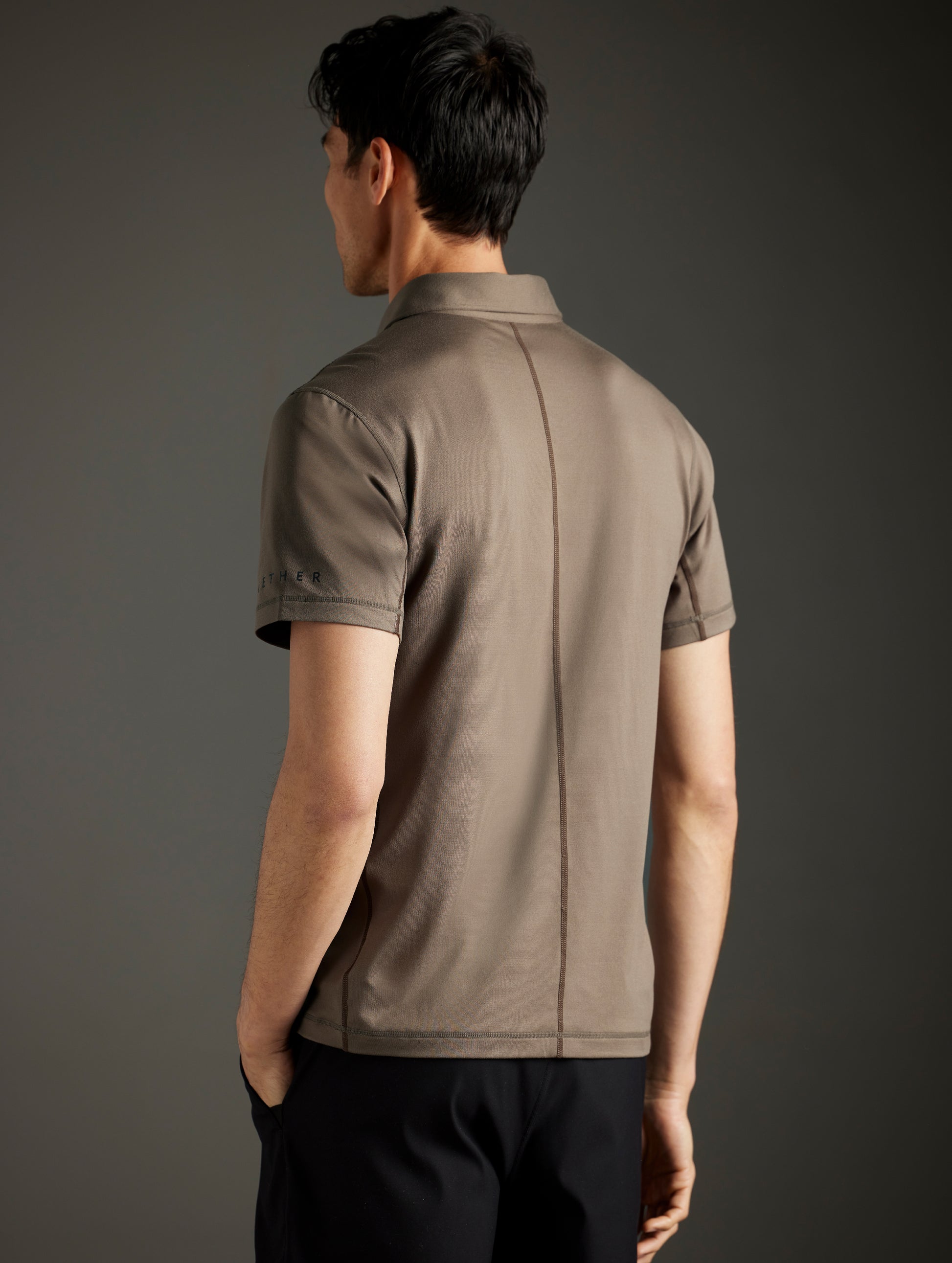 Rear 3/4 body view of man wearing Trek Articulated Polo in Cadet Green from AETHER Apparel.