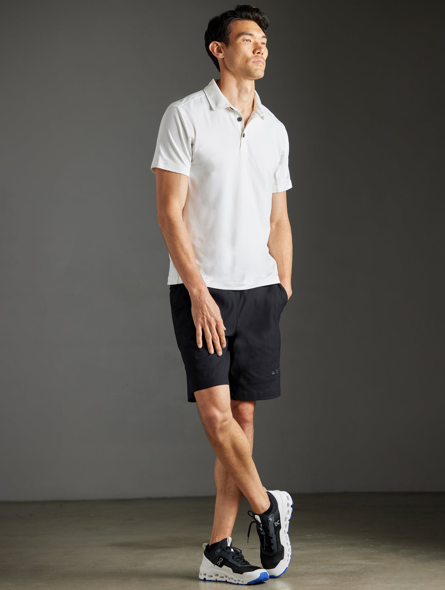Front 3/4 full-body view of man wearing Trek Articulated Polo in Natural White from AETHER Apparel.