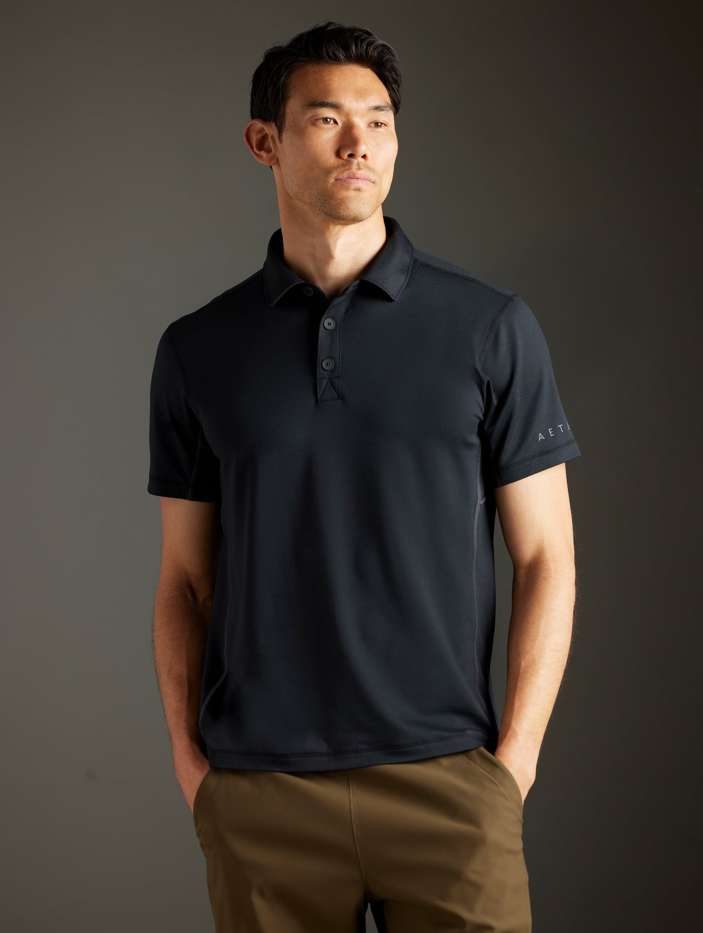 Front body view of man wearing Trek Articulated Polo in Onyx Black from AETHER Apparel.
