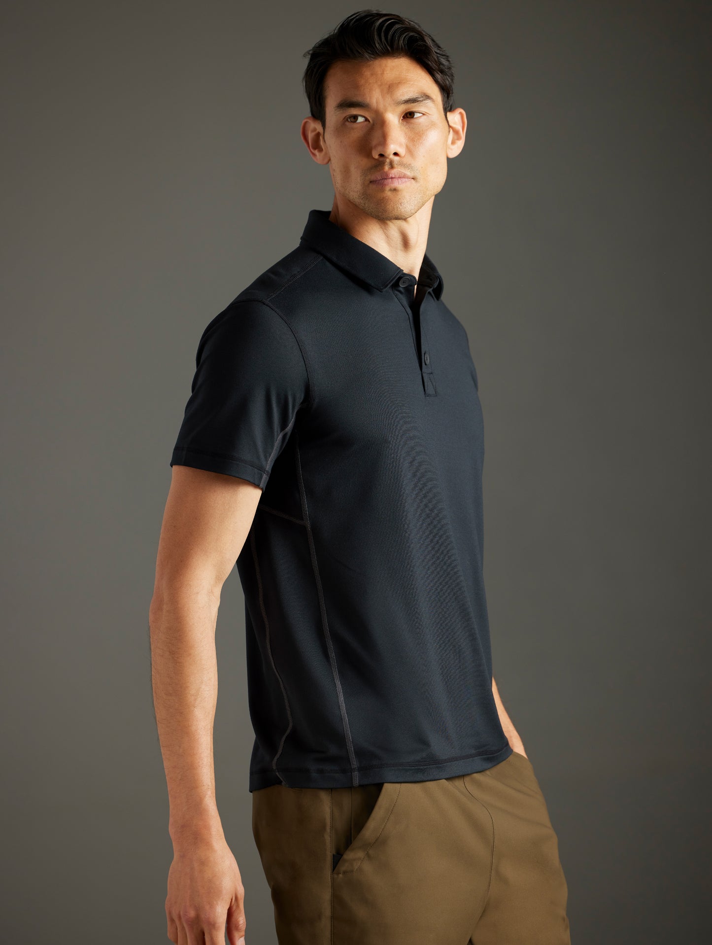 Front 3/4 body view of man wearing Trek Articulated Polo in Onyx Black from AETHER Apparel.