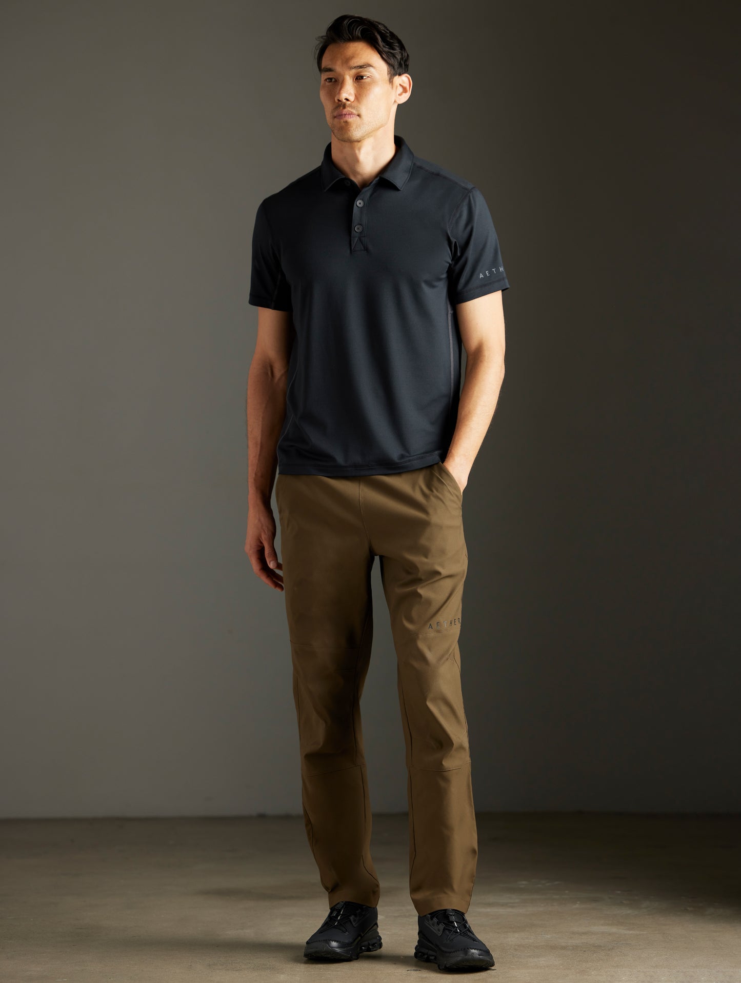 Front full-body view of man wearing Trek Articulated Polo in Onyx Black from AETHER Apparel.
