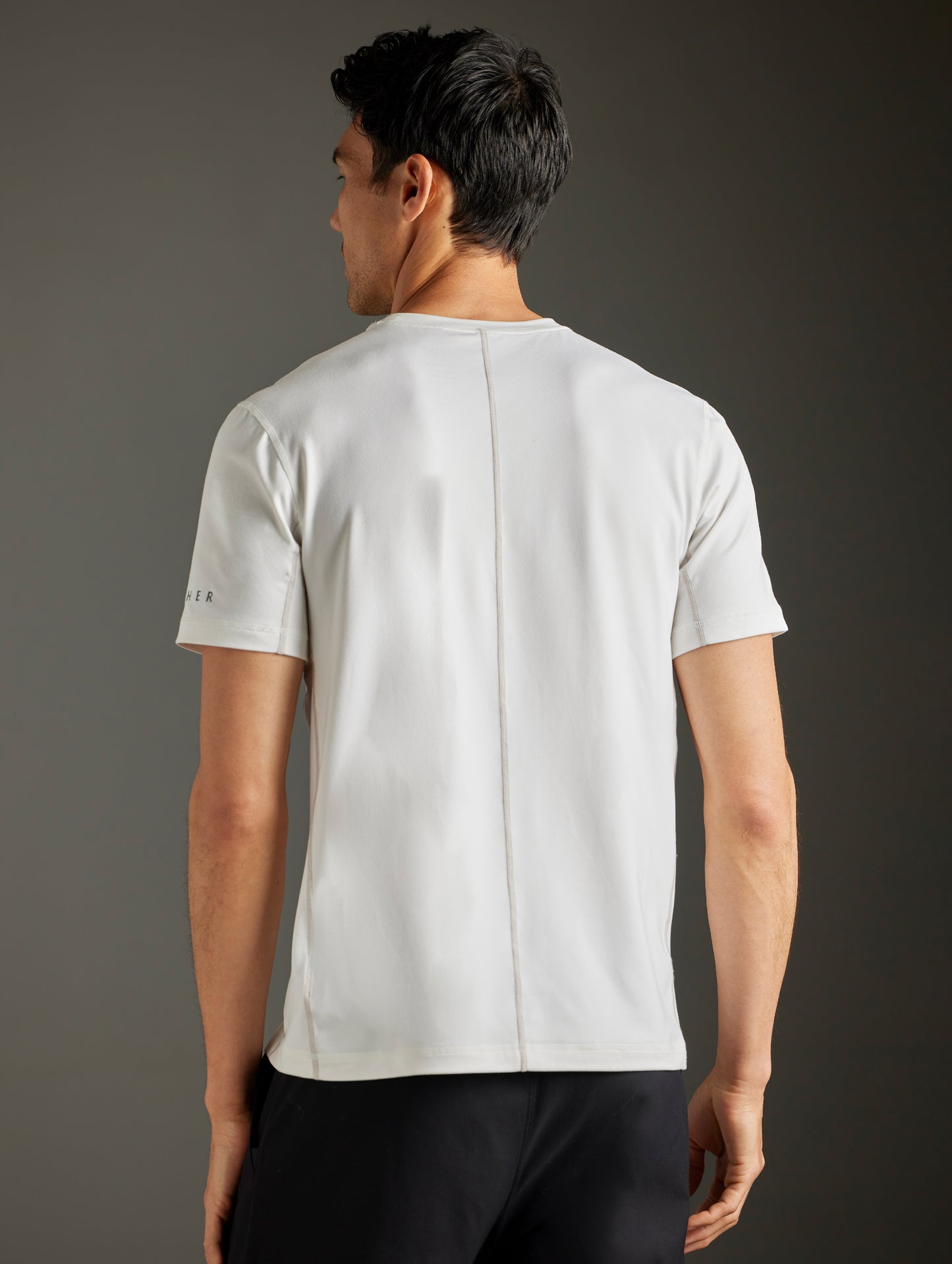 Rear body view of man wearing Trek Articulated Tee in Natural White from AETHER Apparel.