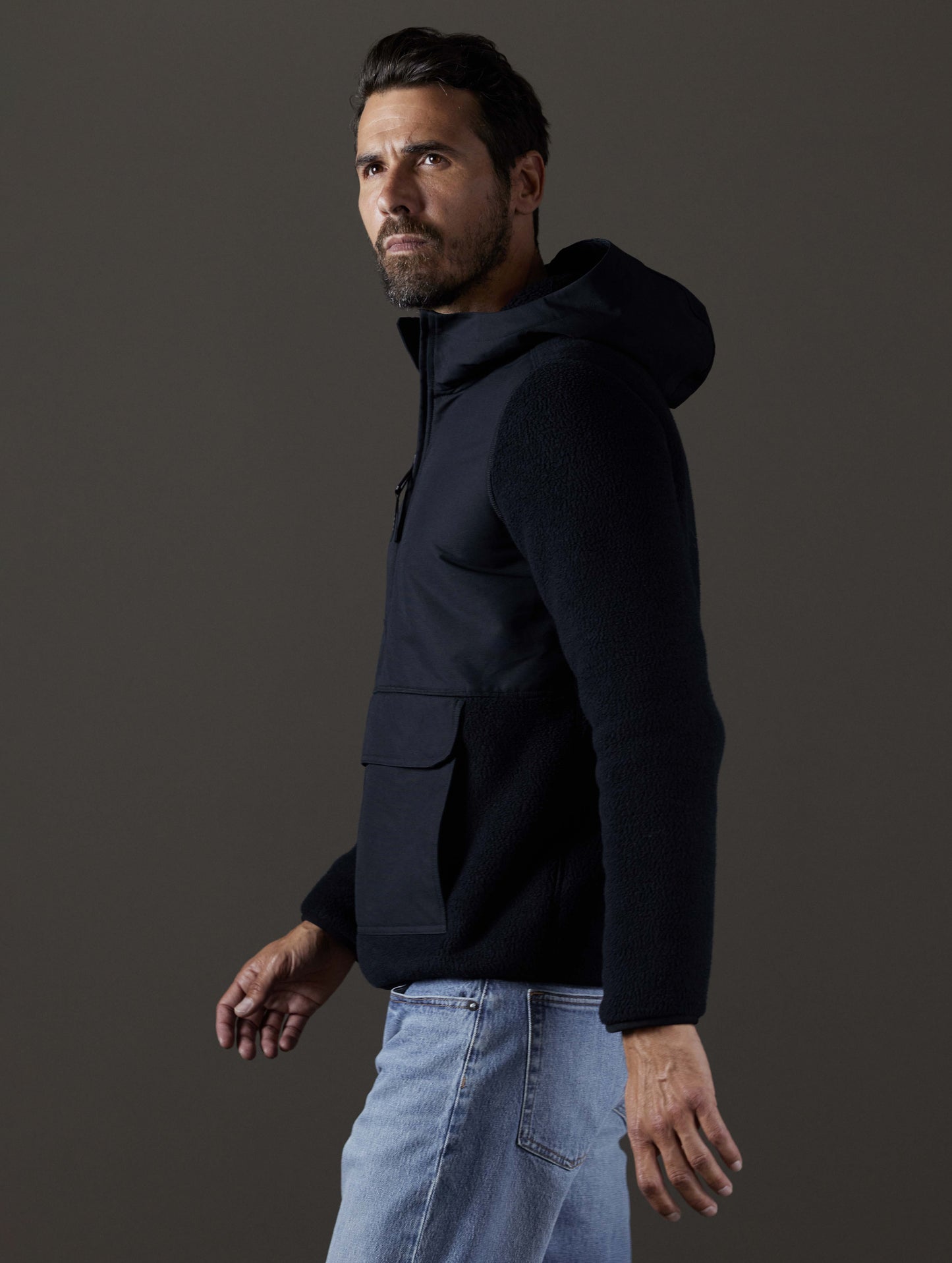 Side profile body view of man wearing Walsh Hooded Anorak in Onyx Black from AETHER Apparel.