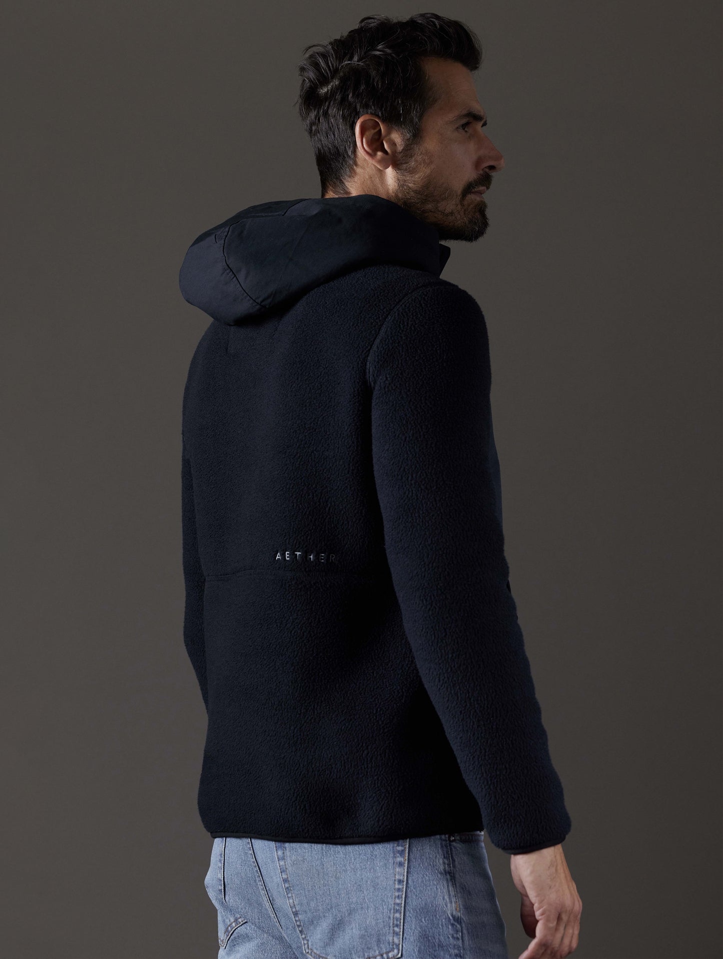 Rear 3/4 body view of man wearing Walsh Hooded Anorak in Onyx Black from AETHER Apparel.