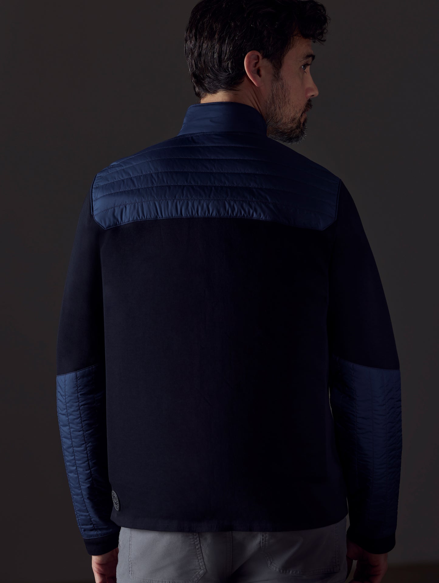 Rear body view of man wearing Watts Technical Jacket in Total Eclipse dark blue from AETHER Apparel.
