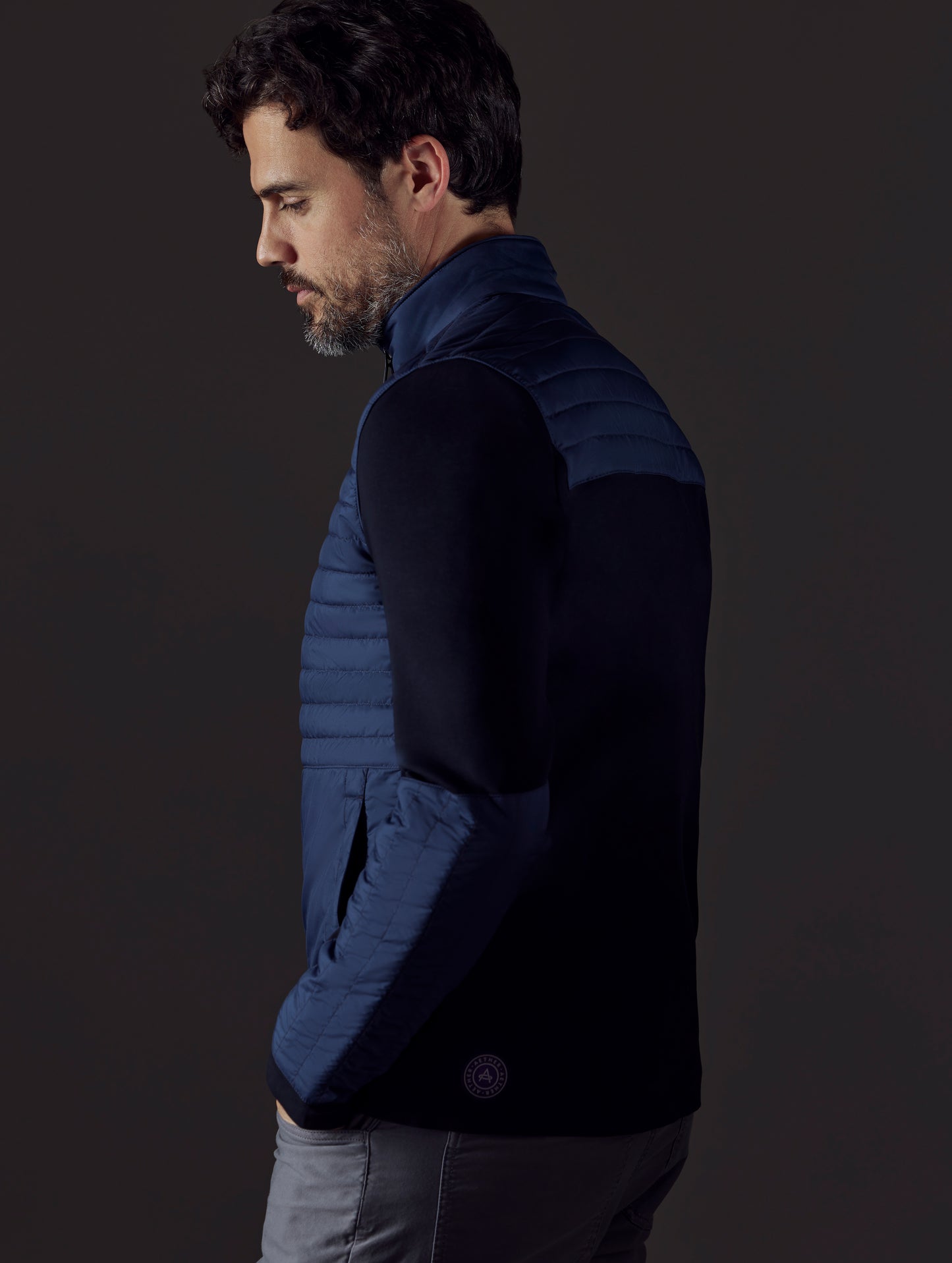Side profile body view of man wearing Watts Technical Jacket in Total Eclipse dark blue from AETHER Apparel.