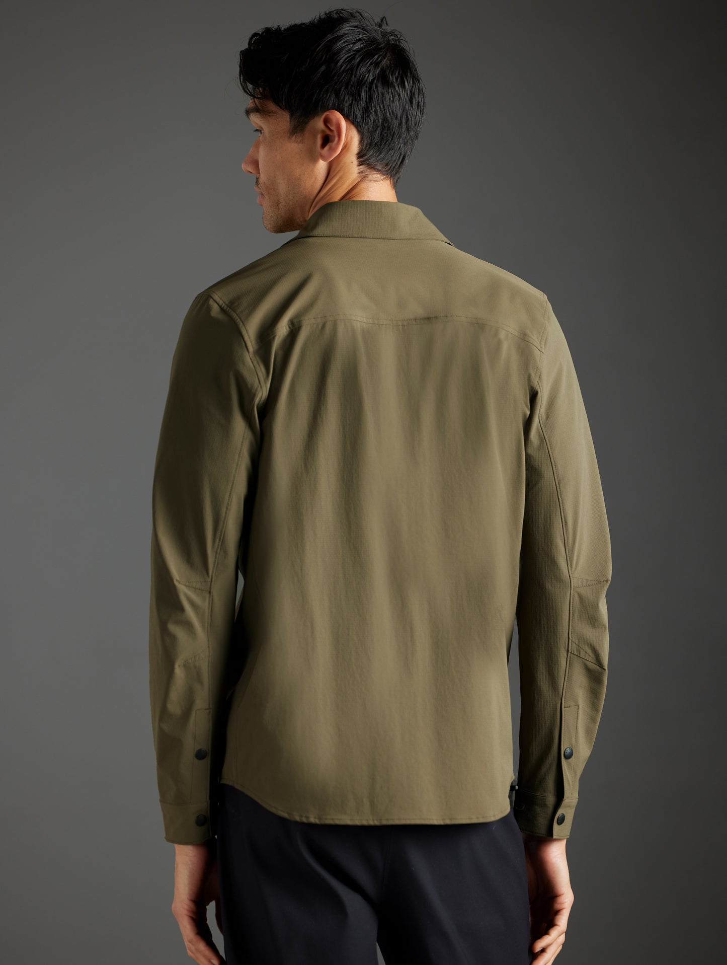 Rear body view of man wearing Wonder Technical Button-Down in Cadet green from AETHER Apparel.